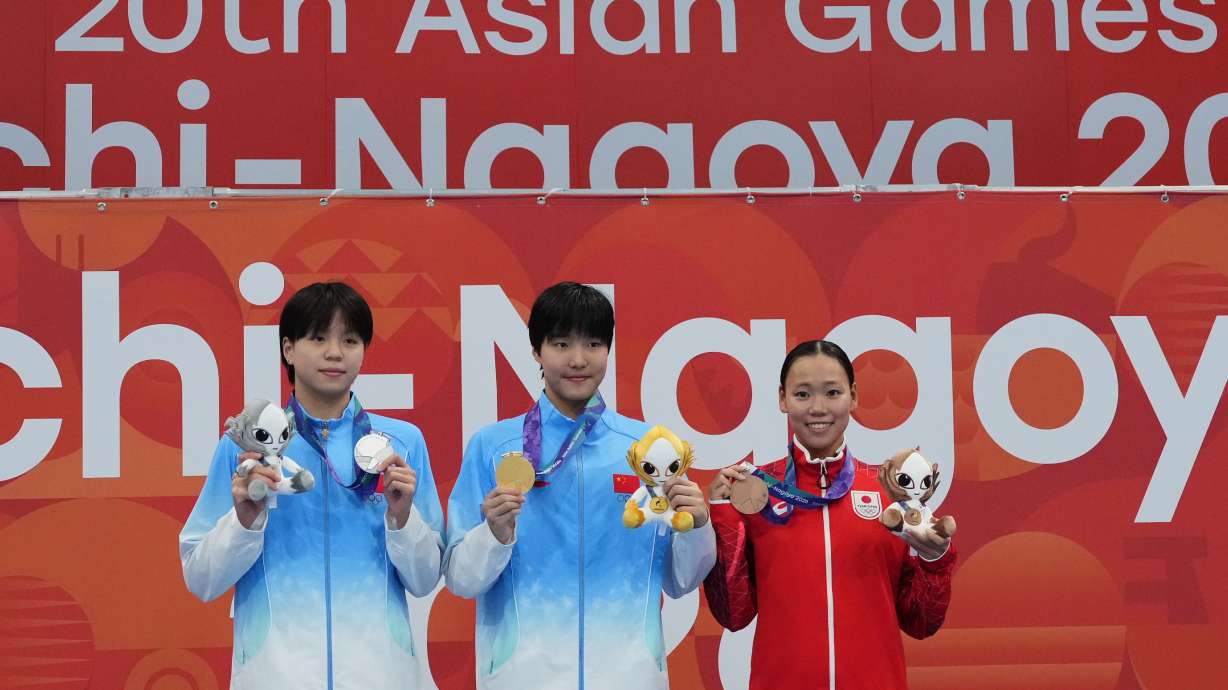 Gold medalist Yu Zidi of China, center, flanked by silver medalist Chang Mohan of China, left, and bronze medalist Misa Okuzono of Japan pose on the podium after the women's 200-meter butterfly final in swimming at the Asian Games in Tokyo, Japan, Sunday, Sept. 20, 2026.