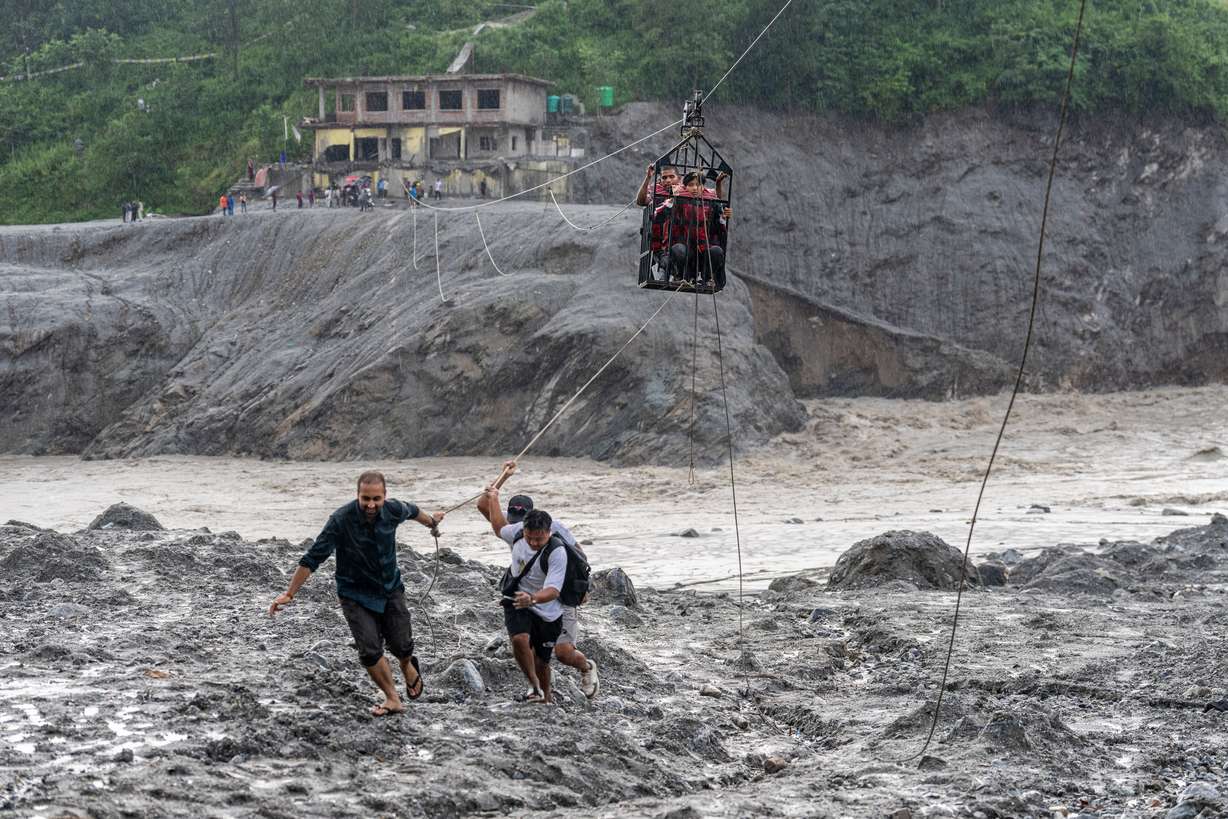Residents pull a newly installed zipline to help people commute across the Trishuli River in the aftermath of floods at Bidur in Nepal's Nuwakot district, Nepal, Sept. 2.