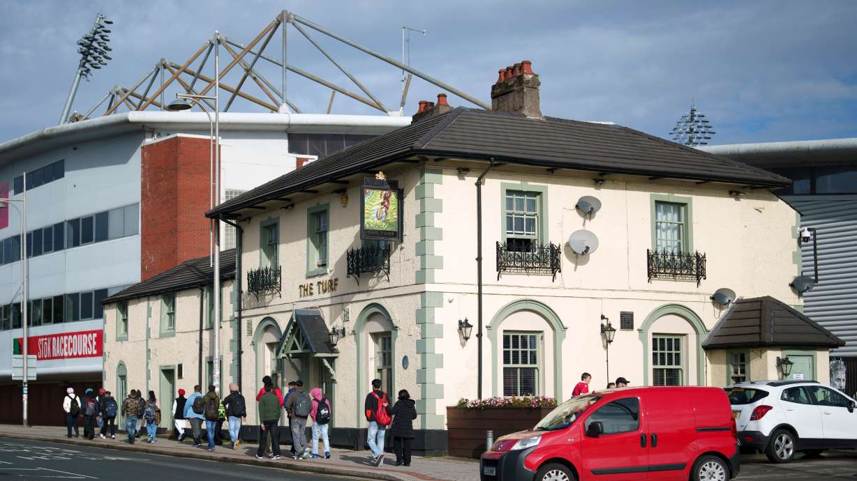 FILE - Members of the public walk past the Turf Pub next to Wrexham Football Club's Racecourse Ground in Wrexham, Wales, Monday, Oct. 7, 2024.
