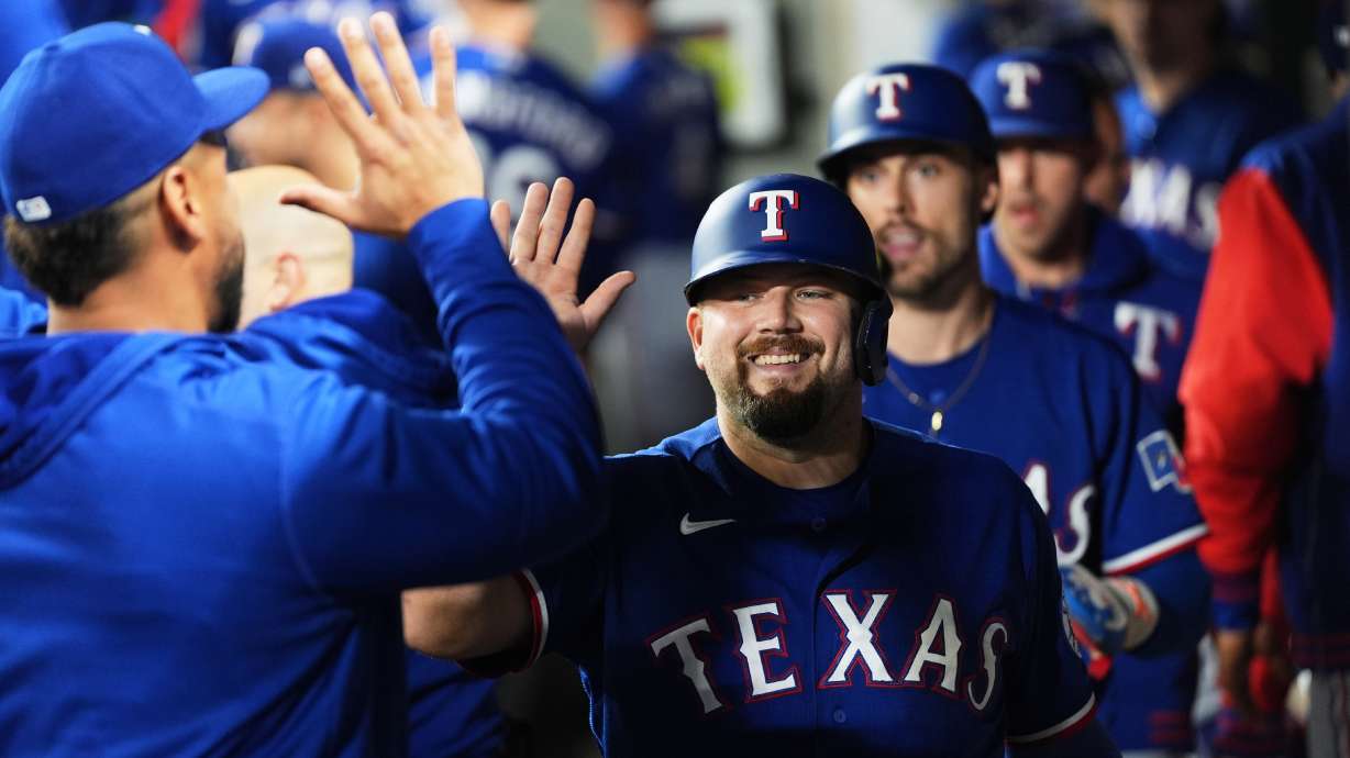 Texas Rangers' Jake Burger is greeted in the dugout after scoring on a two-run single from Justin Foscue during the fourth inning of a baseball game against the Seattle Mariners, Tuesday, Sept. 8, 2026, in Seattle.