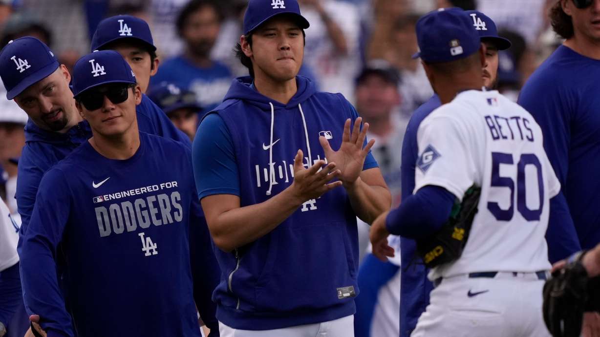 Los Angeles Dodgers' Mookie Betts, right, is congratulated by Shohei Ohtani, center, and Yoshinobu Yamamoto after the Dodgers defeated the San Francisco Giants in a baseball game Sunday, Sept. 20, 2026, in Los Angeles.