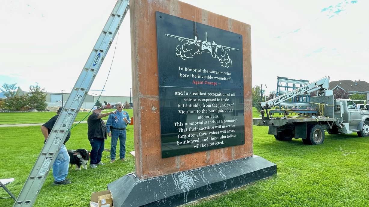 The Agent Orange memorial in Sunset sought by Syracuse Vietnam War veteran Larry Kerr is largely complete. Kerr, right, is pictured Monday at the installation of the last black marble slab on the opposite side of the monument.