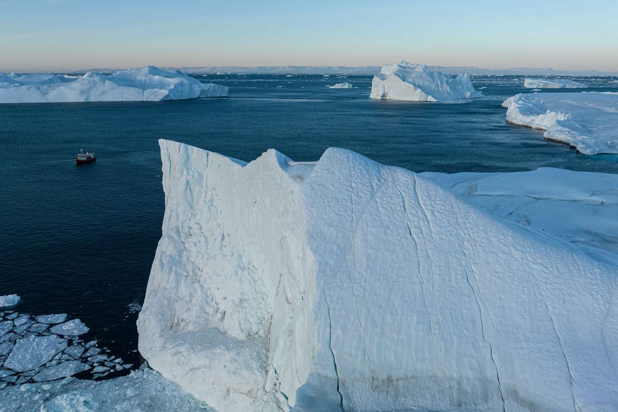 A fishing boat pulls a net up with fish in front of an iceberg at Disko Bay near Ilulissat, Greenland, on Jan. 29. The United States, Denmark and Greenland signed a landmark agreement on Tuesday to increase U.S. military presence and more.