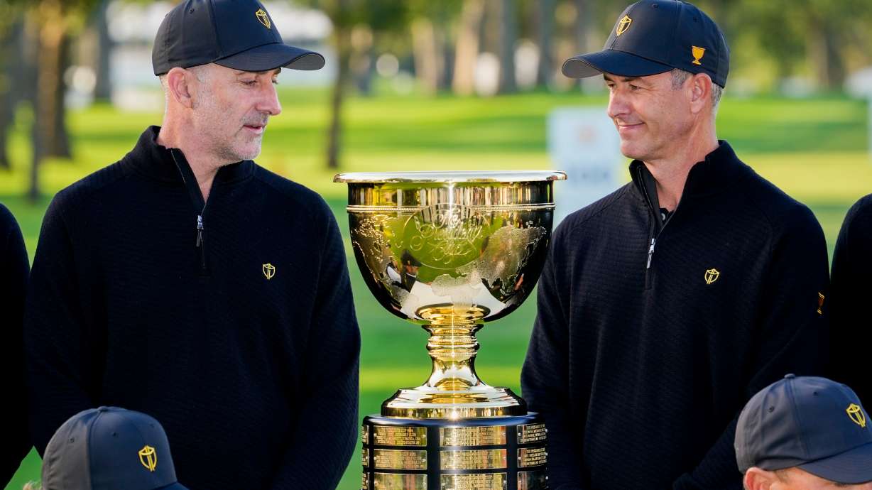 International team captain Geoff Ogilvy, of Australia, left, and player Adam Scott, of Australia, look at the Presidents Cup trophy during a team portrait prior to the start of the Presidents Cup golf tournament against the USA team at Medinah Country Club, Wednesday, Sept. 23, 2026, in Medinah, Ill.