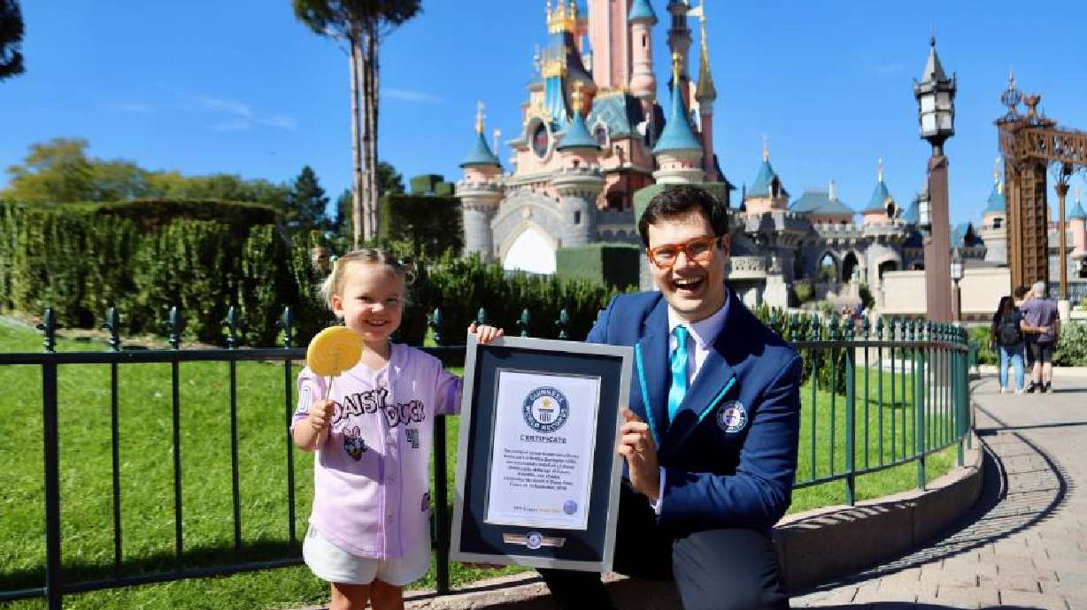 Bootsie Darrington poses for a photo at Disney Adventure World Paris. Guinness World Records Adjudicator William Sinden presented Bootsie with a certificate for becoming the youngest person to visit every Disney park in the world.