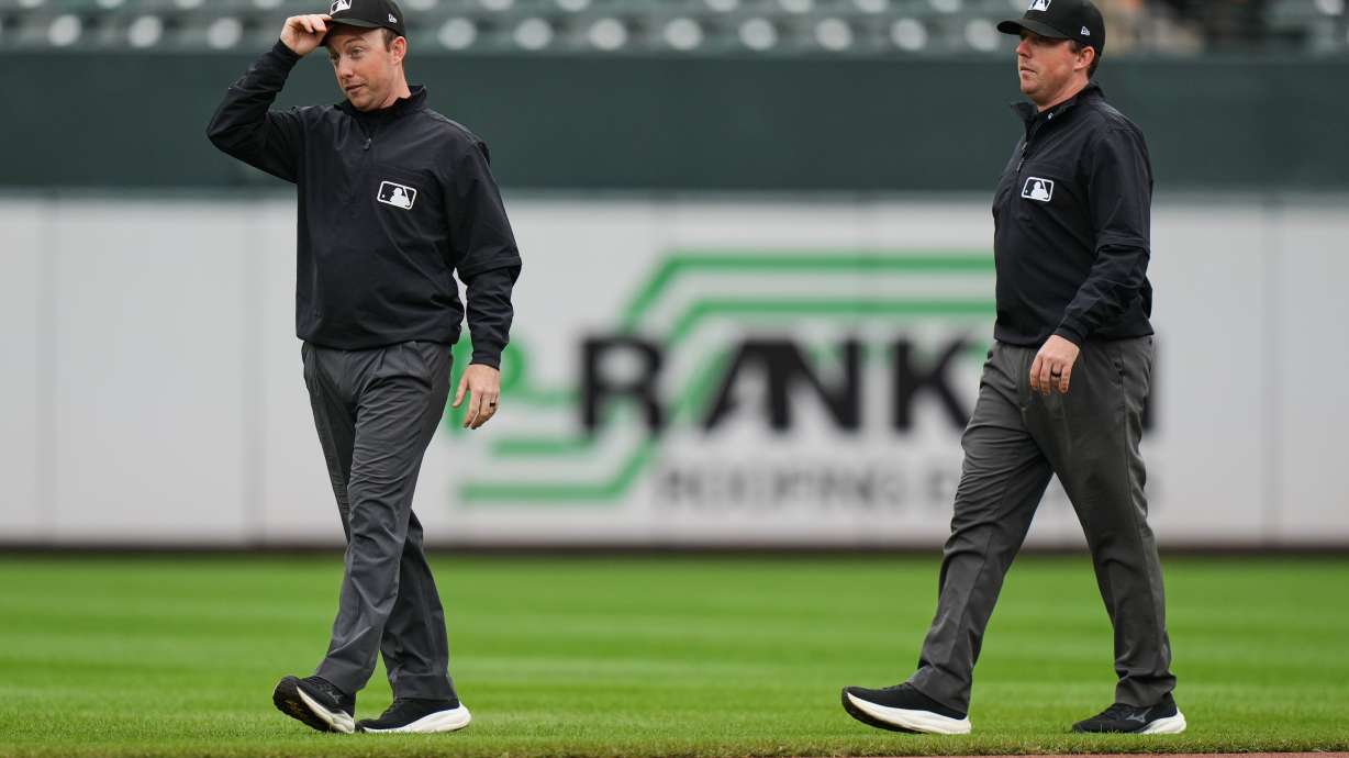Second base umpire Tyler Jones, left, and his twin brother first base umpire Austin Jones walk on the field during the second inning in the first baseball game of a doubleheader between the Baltimore Orioles and the Toronto Blue Jays, Wednesday, Sept. 23, 2026, in Baltimore.