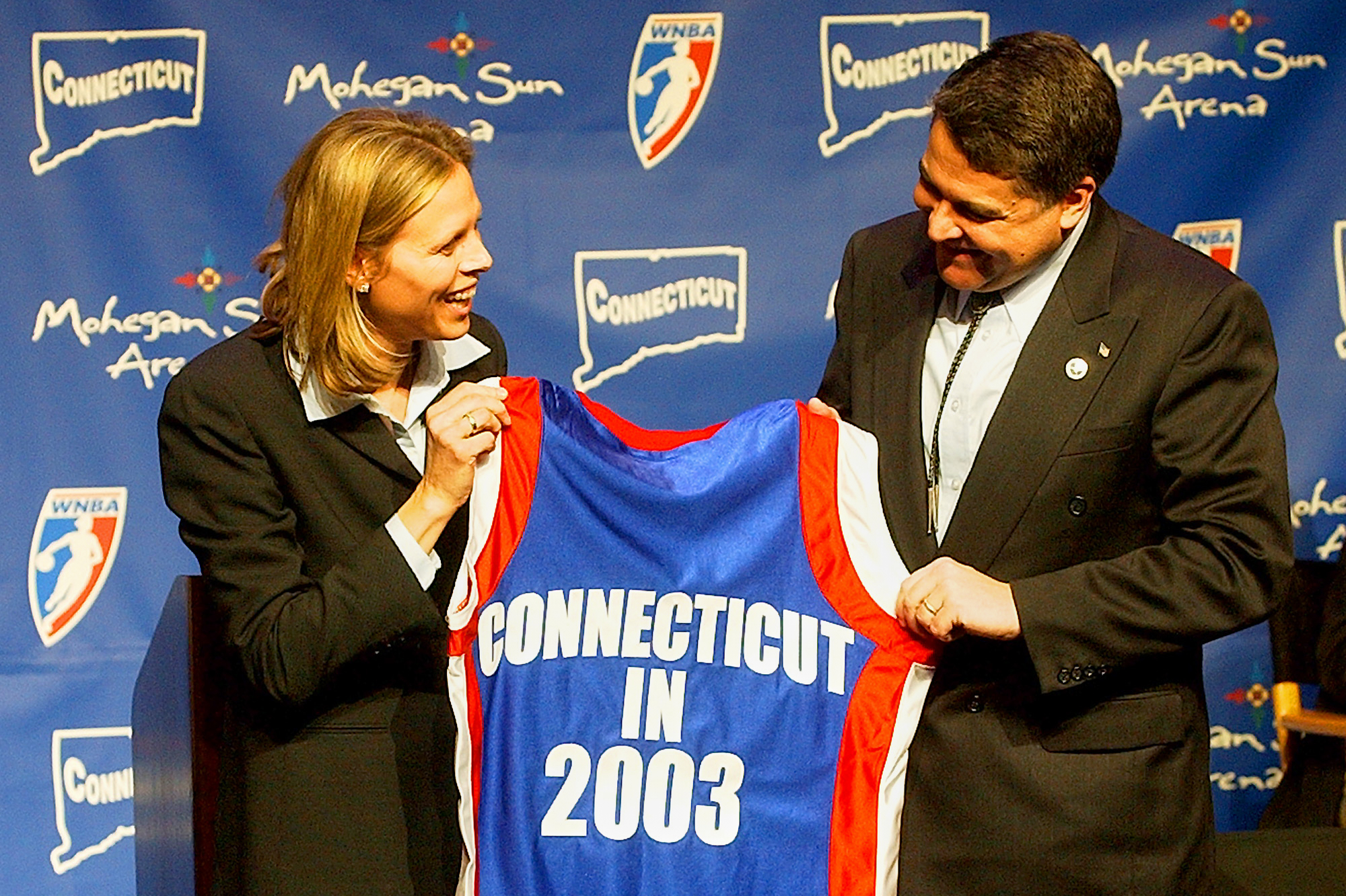 FILE - WNBA League President Val Ackerman, left, and Mohegan Tribe Tribal Chairman Mark Brown hold a basketball shirt of the type that will be worn by the WNBA team Connecticut Sun during a news conference Tuesday, Jan. 28, 2003, at the Mohegan Sun Arena in Uncasville, Conn. 