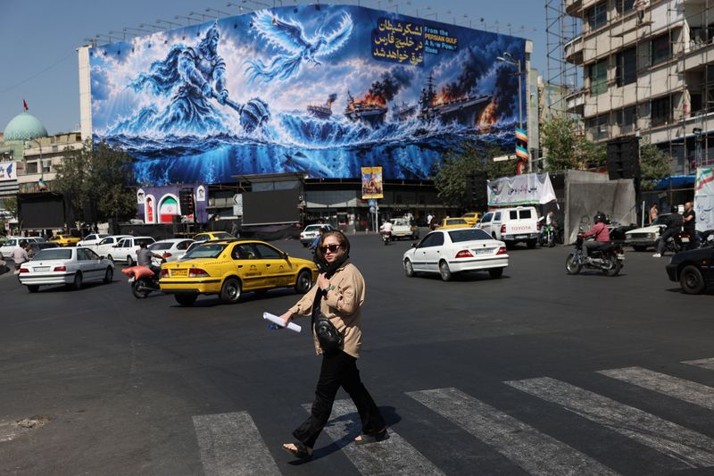 A woman walks past a billboard about the Strait of Hormuz, on a building in Tehran, Iran, Sept. 16. The U.S. and Iran were discussing a phased plan to end their 7-month-old war on Thursday, sources told Reuters.