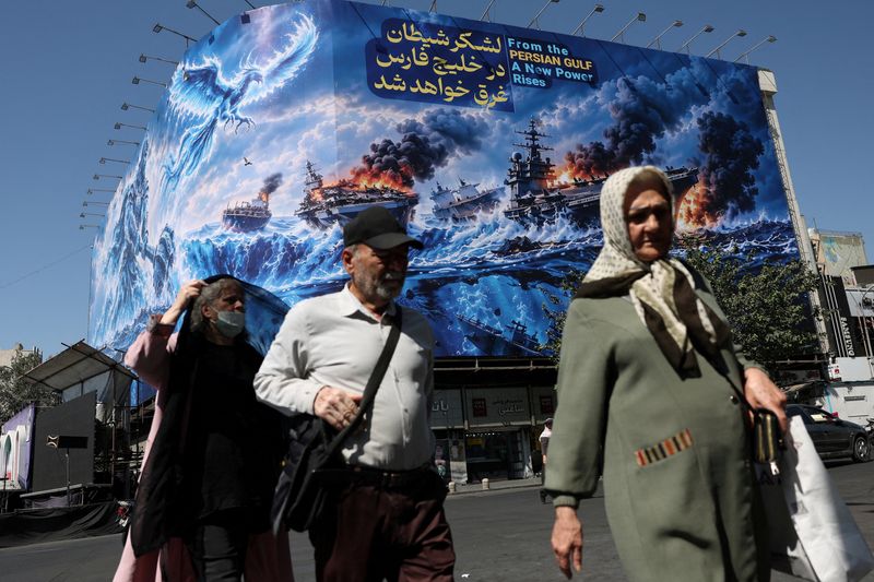 People walk past a billboard about the Strait of Hormuz, on a building in Tehran, Iran, Sep. 16.
