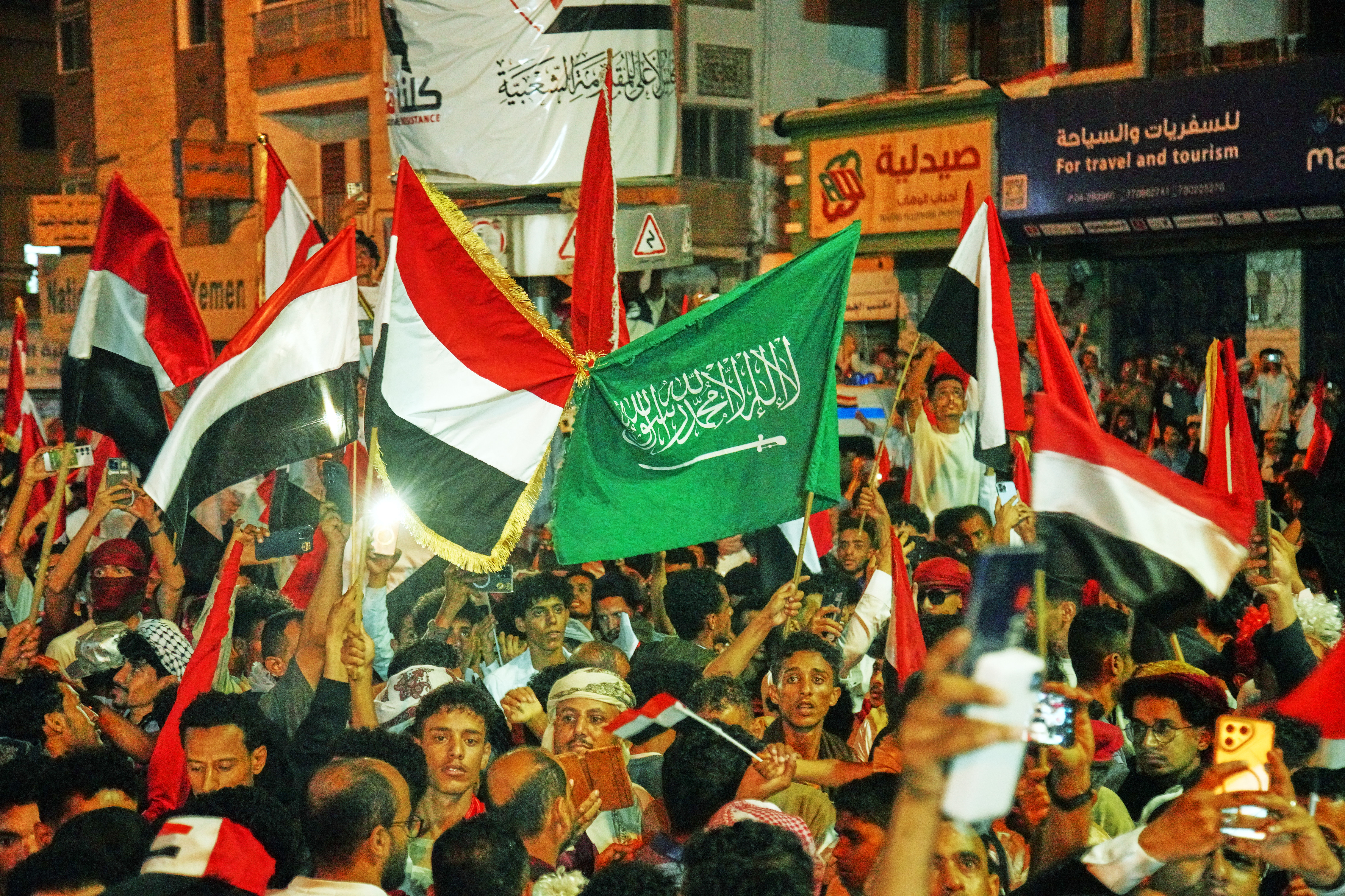 Yemenis wave national and Saudi flags as they celebrate the 64th anniversary of the Saturday Revolution in Taiz, Yemen, Friday.