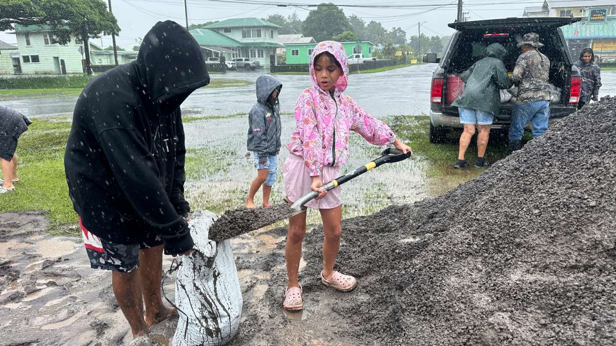 Kenzielynn Kekoa, of Hilo, Hawaii, helps her family fill sand bags as Hurricane Nolo approaches in Hilo, Friday. Hawaii is bracing for another tropical cyclone threat from Hurricane Nolo.