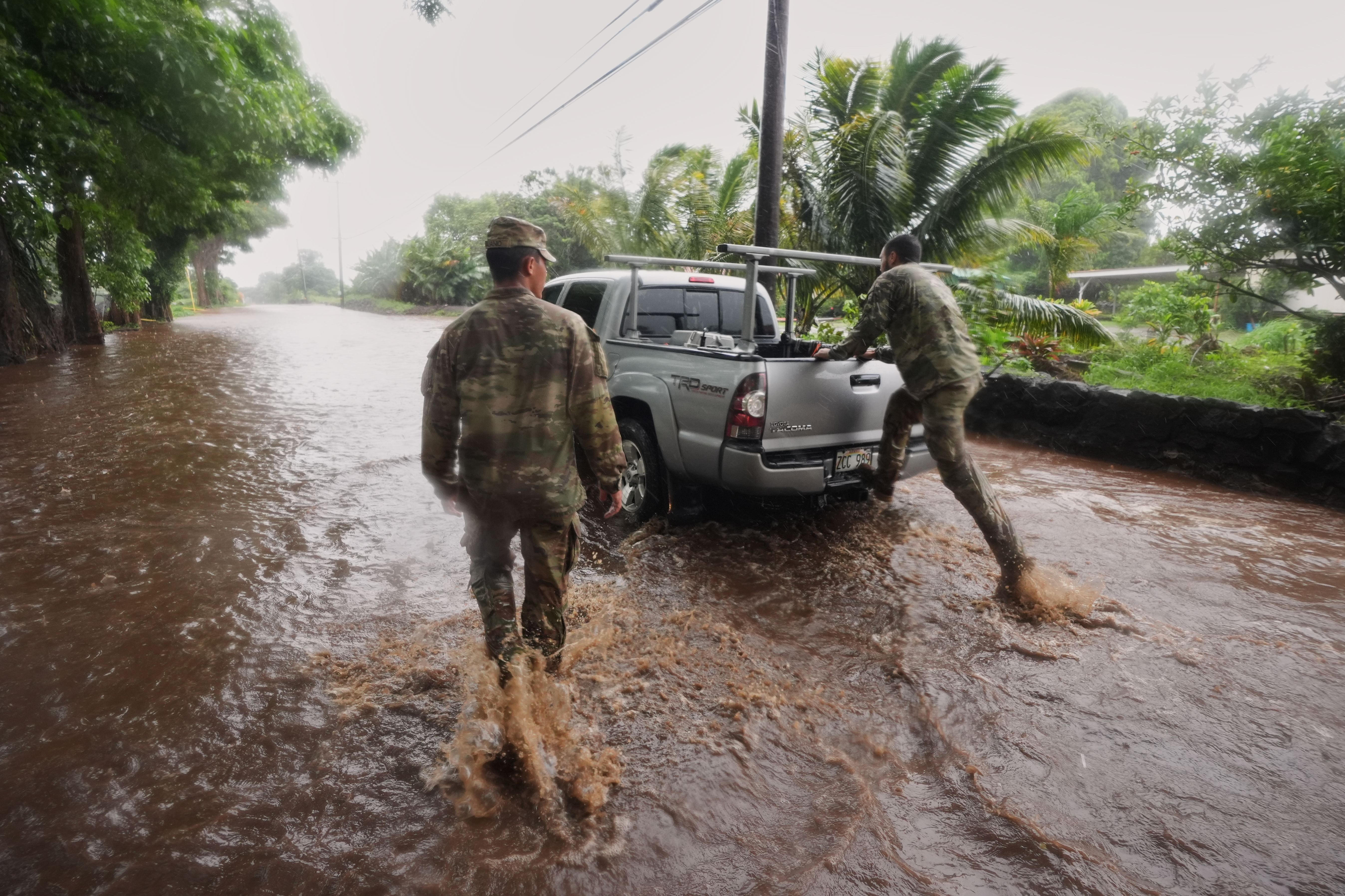 Members of the Hawaii Army National Guard help a resident leave his home as rainwater from nearby Hurricane Nolo floods a section of Mamalahoa Highway on Saturday, near Naalehu, Hawaii.