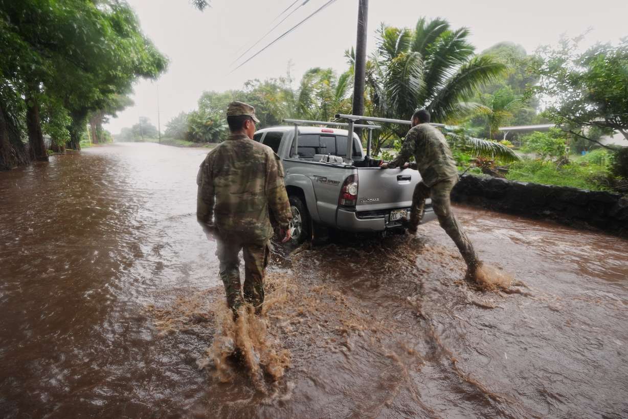 Members of the Hawaii Army National Guard help a resident leave his home as rainwater from nearby Hurricane Nolo floods a section of Mamalahoa Highway on Saturday, near Naalehu, Hawaii.