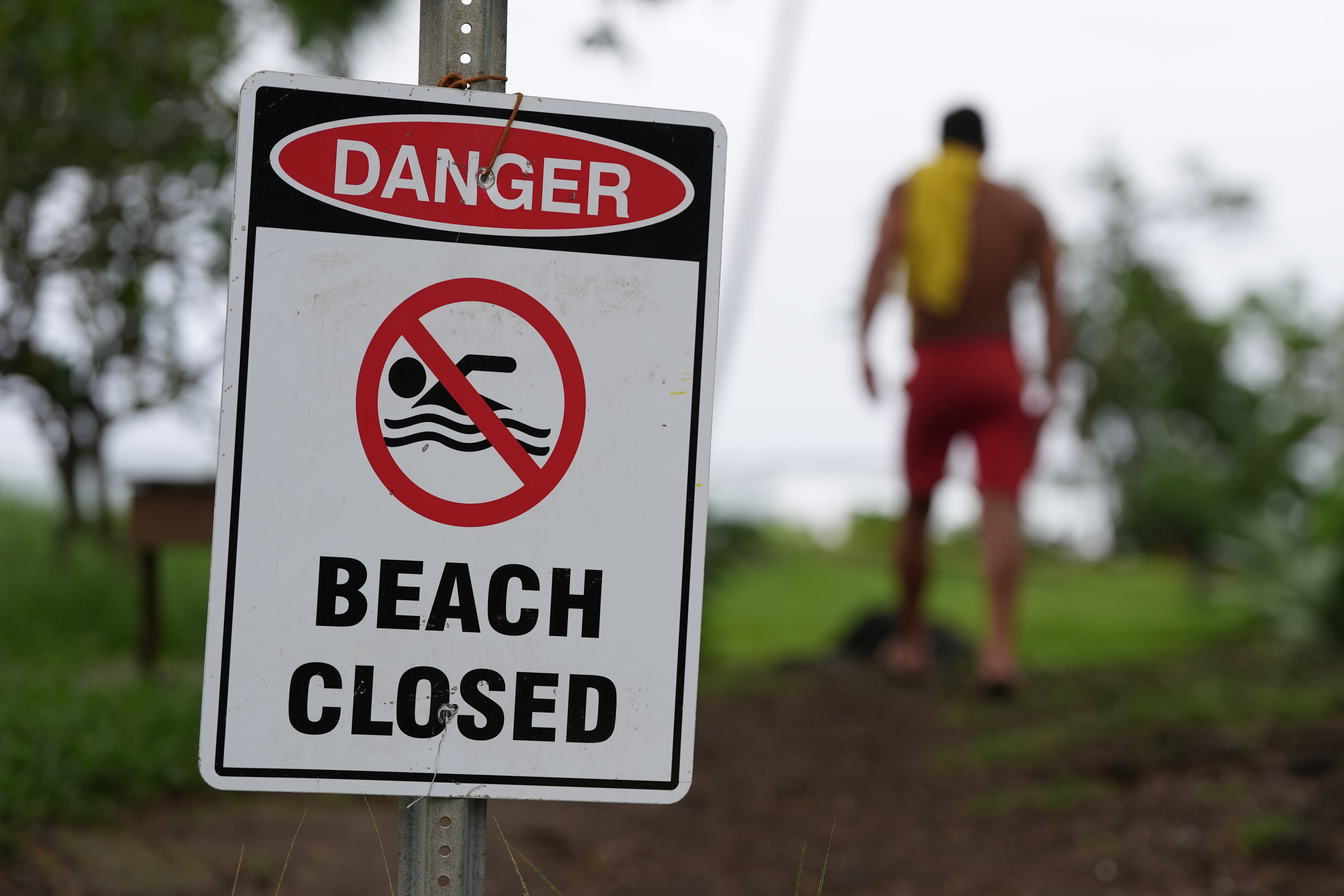 A lifeguard walks back to his tower after adjusting a beach closure sign as Hurricane Nolo sits nearby Saturday, in Hilo, Hawaii.