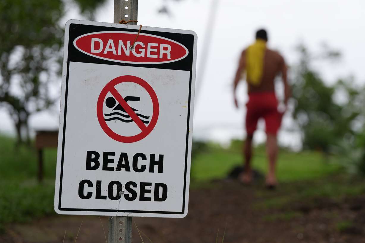 A lifeguard walks back to his tower after adjusting a beach closure sign as Hurricane Nolo sits nearby Saturday, in Hilo, Hawaii.