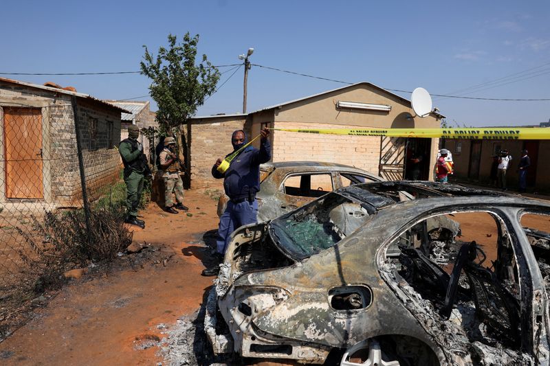 Emergency personnel cordon off an area next to burnt vehicles at the site of a deadly shooting at a tavern in Wedela township, southwest of Johannesburg, South Africa, September 27, 2026.