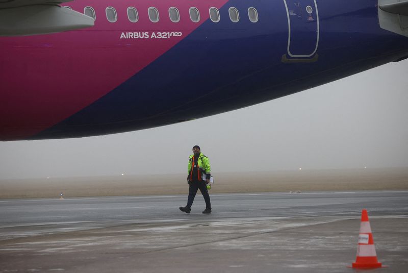 FILE PHOTO: A ground handling worker walks on the apron near a Wizz Air Airbus A321neo aircraft, registration 9H-WMI, at Warsaw-Modlin Airport in Modlin, Poland, December 1, 2025.