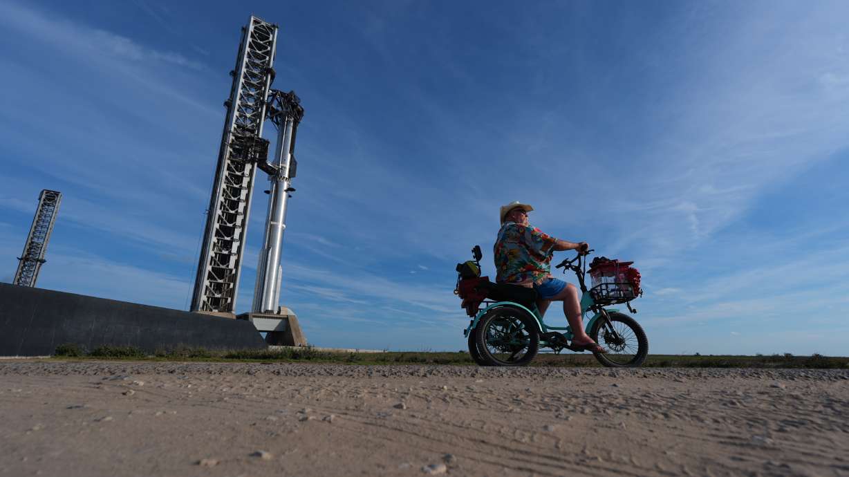 David Orr rides his bike past SpaceX's mega rocket Starship as it prepared for a test flight from Starbase, Texas, on Sunday. Starship launched and returned to Earth more quickly than expected Monday.