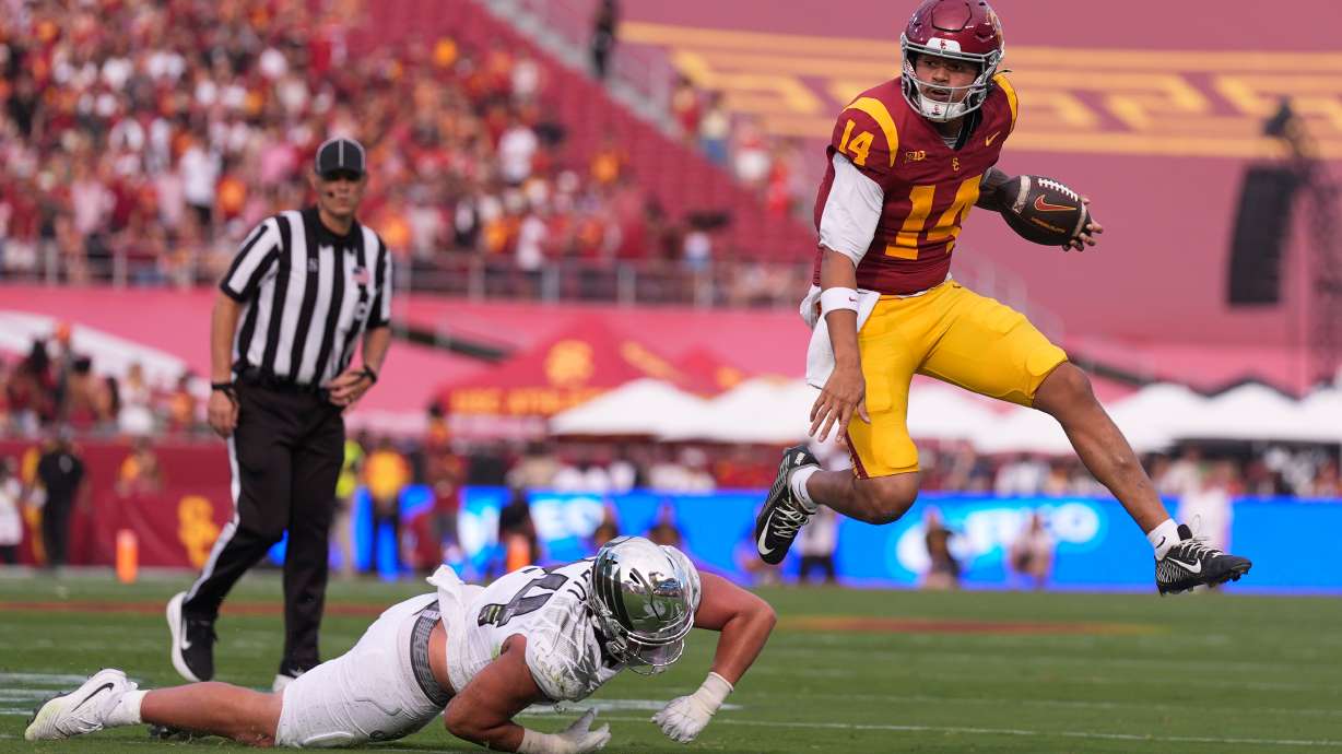 Southern California quarterback Jayden Maiava, right, jumps away from Oregon linebacker Teitum Tuioti during the first half of an NCAA college football game, Saturday, Sept. 26, 2026, in Los Angeles.