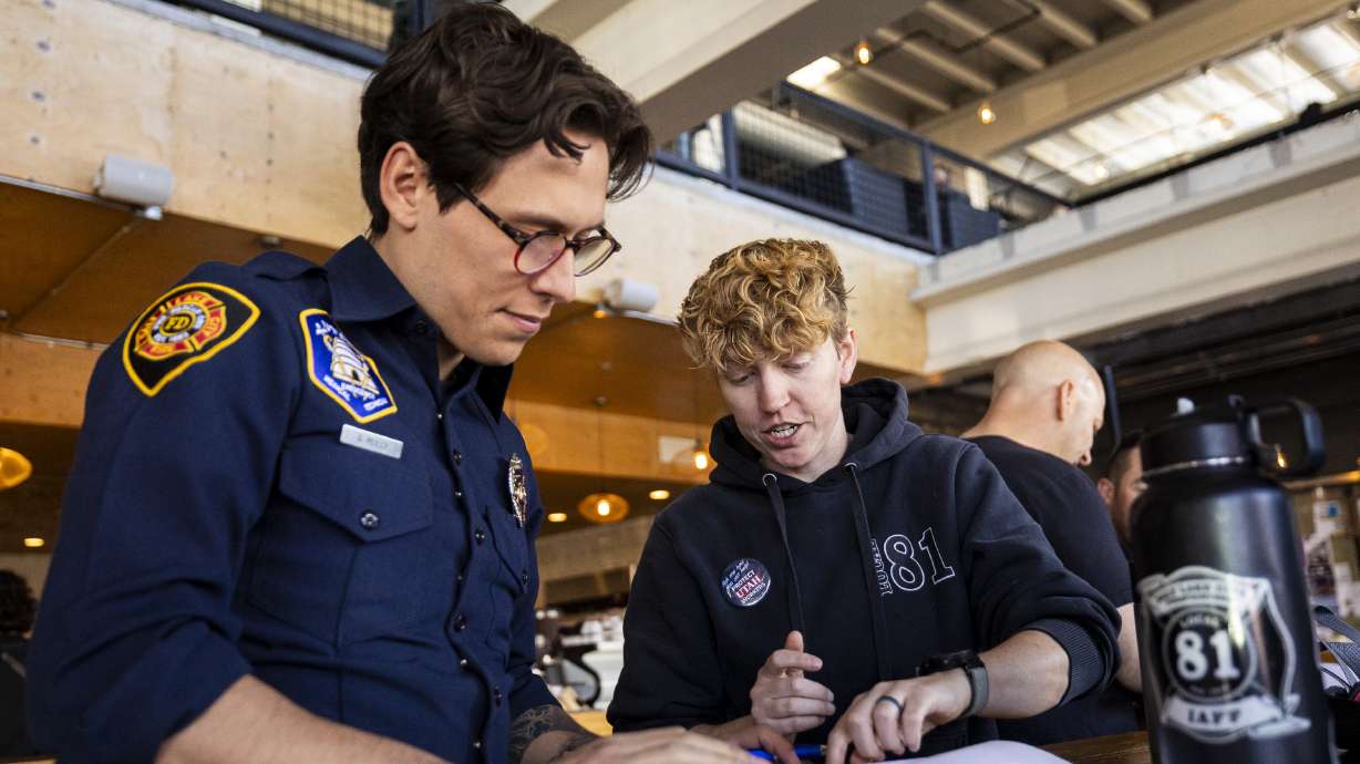 Salt Lake City firefighters Gabe Reilly, left, and Devon Keir, right, at a signature-gathering event for a referendum to repeal HB267 on Wednesday, March 26, 2025.