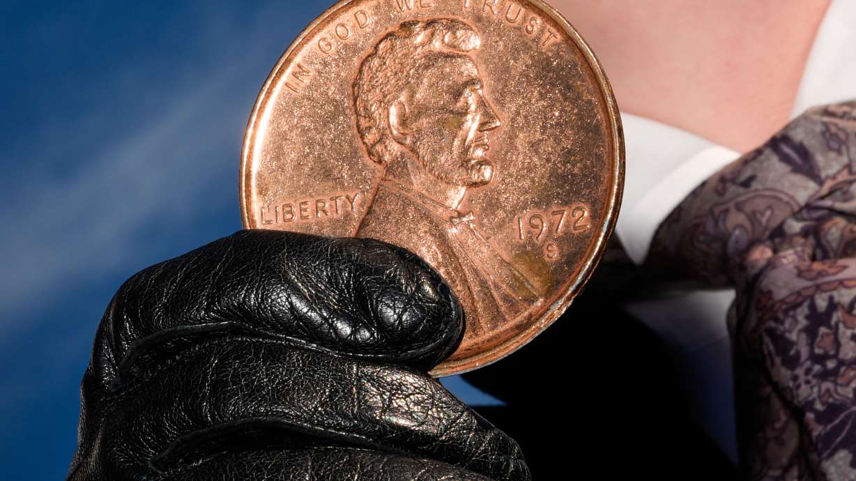 A person holds a giant penny at a mock funeral for the coin, Dec. 20, in front of the Lincoln Memorial in Washington. Congress officially has voted to end production of the penny.