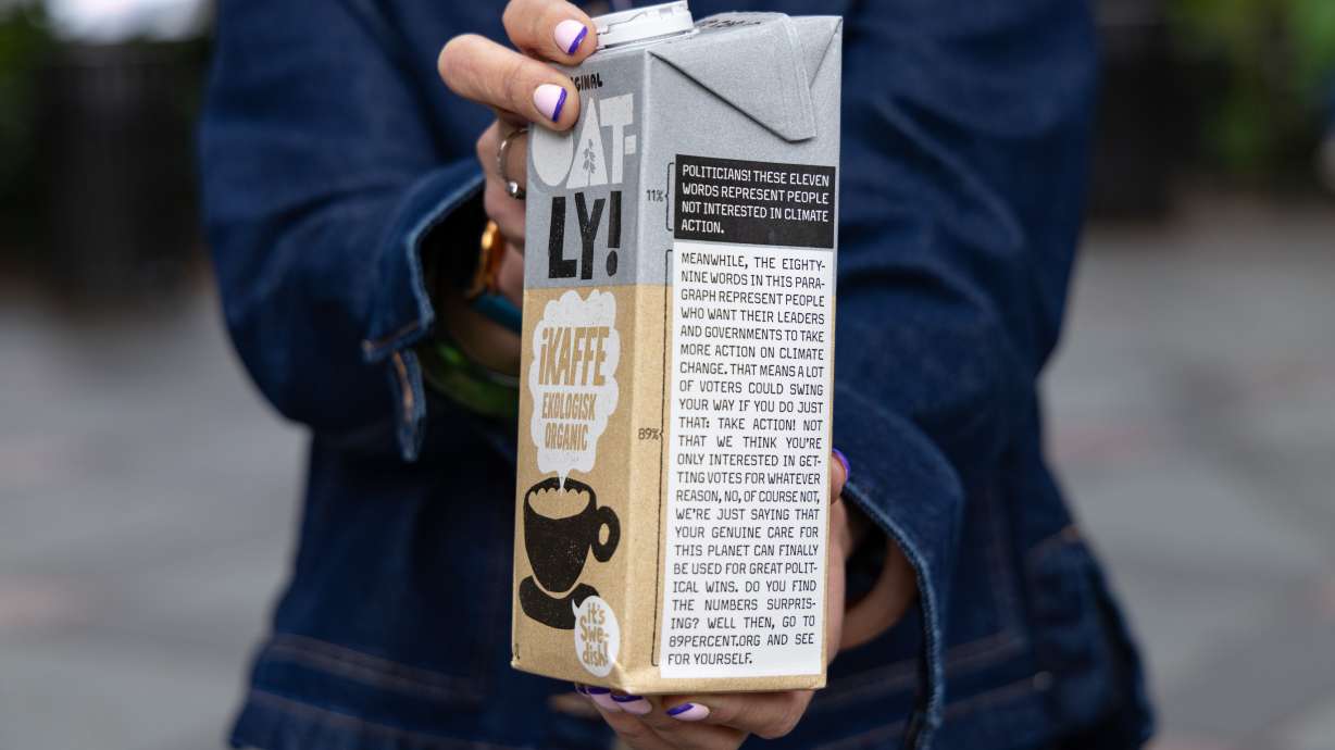 Caroline Reid, with the Swedish oat milk company Oatly, shows a sample of the company's new milk carton climate campaign for New York Climate Week on Sept. 23, in New York.