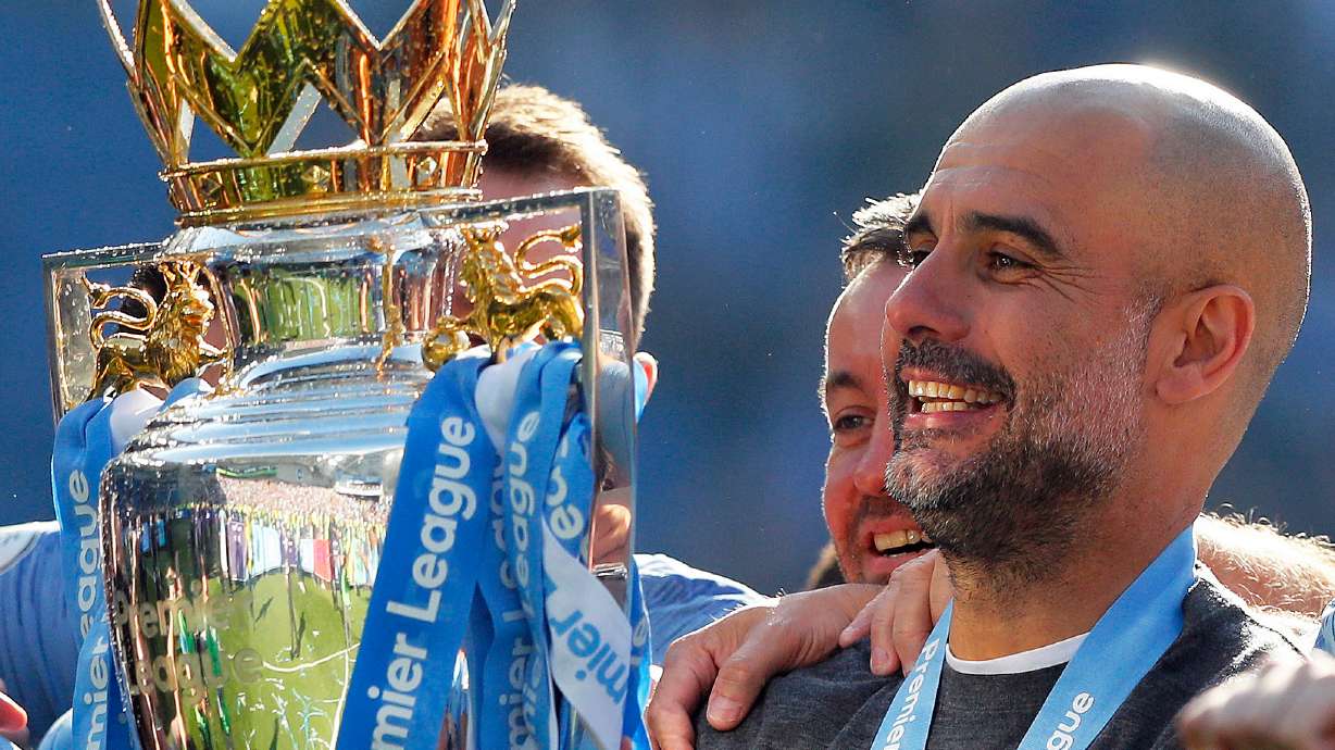 FILE - Manchester City coach Pep Guardiola lifts the English Premier League trophy after the English Premier League soccer match between Brighton and Manchester City at the AMEX Stadium in Brighton, England, Sunday, May 12, 2019.