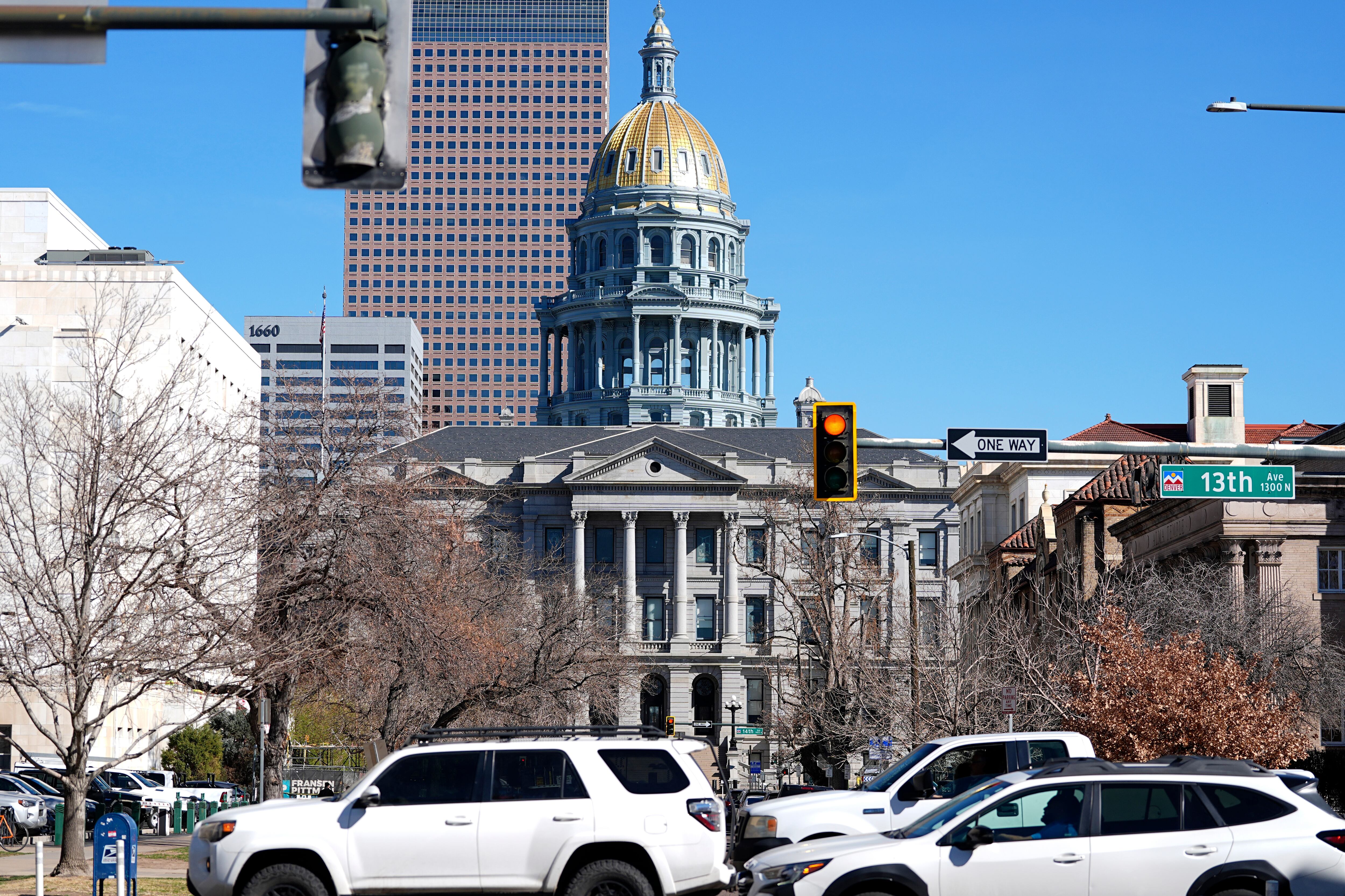 Traffic hurries along 13th Avenue in the foreground as the gold dome of the State Capitol gleams in the early-morning sun March 25, 2025, in Denver.
