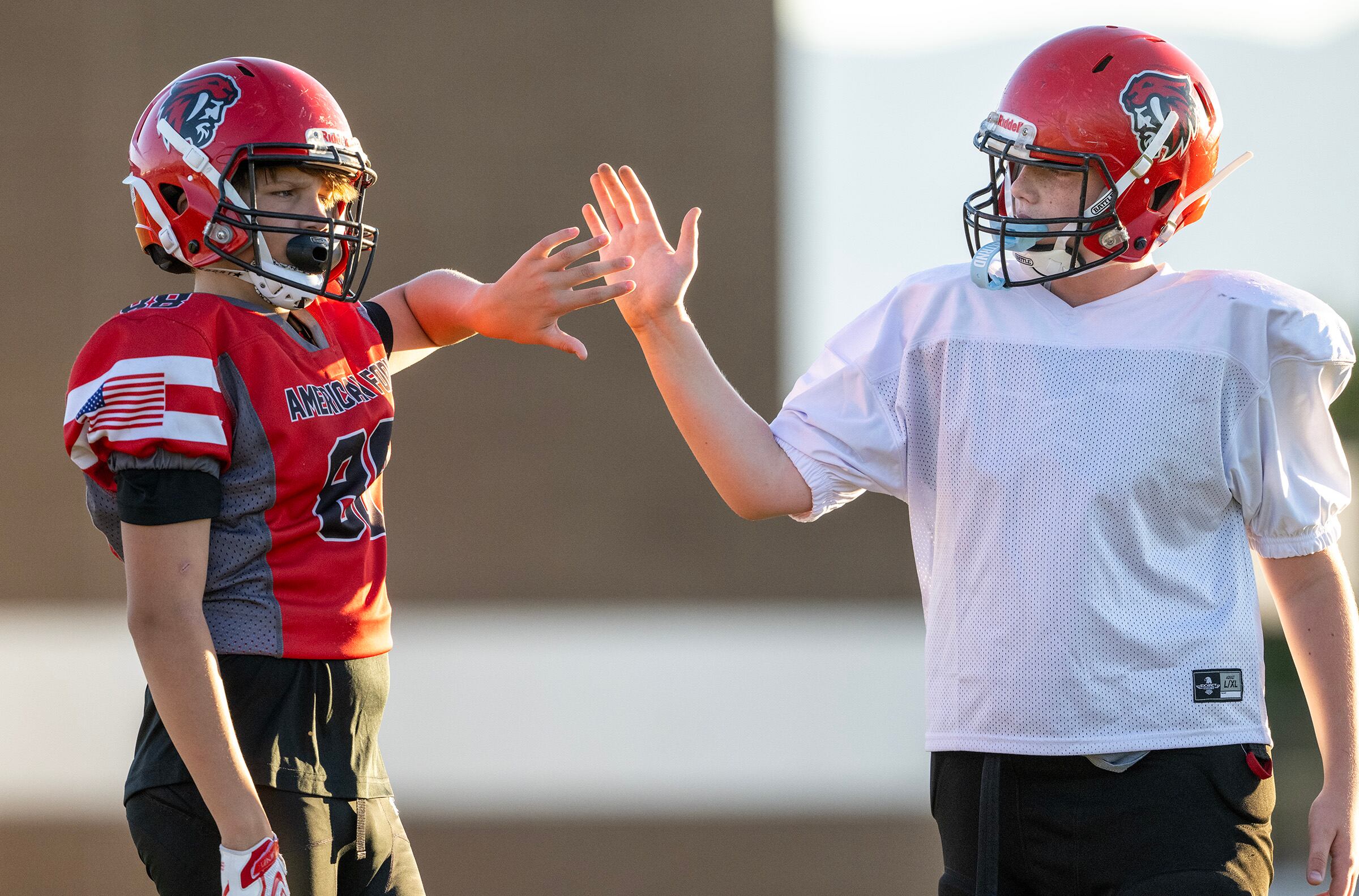 Logan North and Klasusian Sorensen high-five each other as members of a youth football team in American Fork go through their practice at American Fork Jr. High on Sept. 23. A new poll showed parents are comfortable with kids playing football nationwide — to an extent.