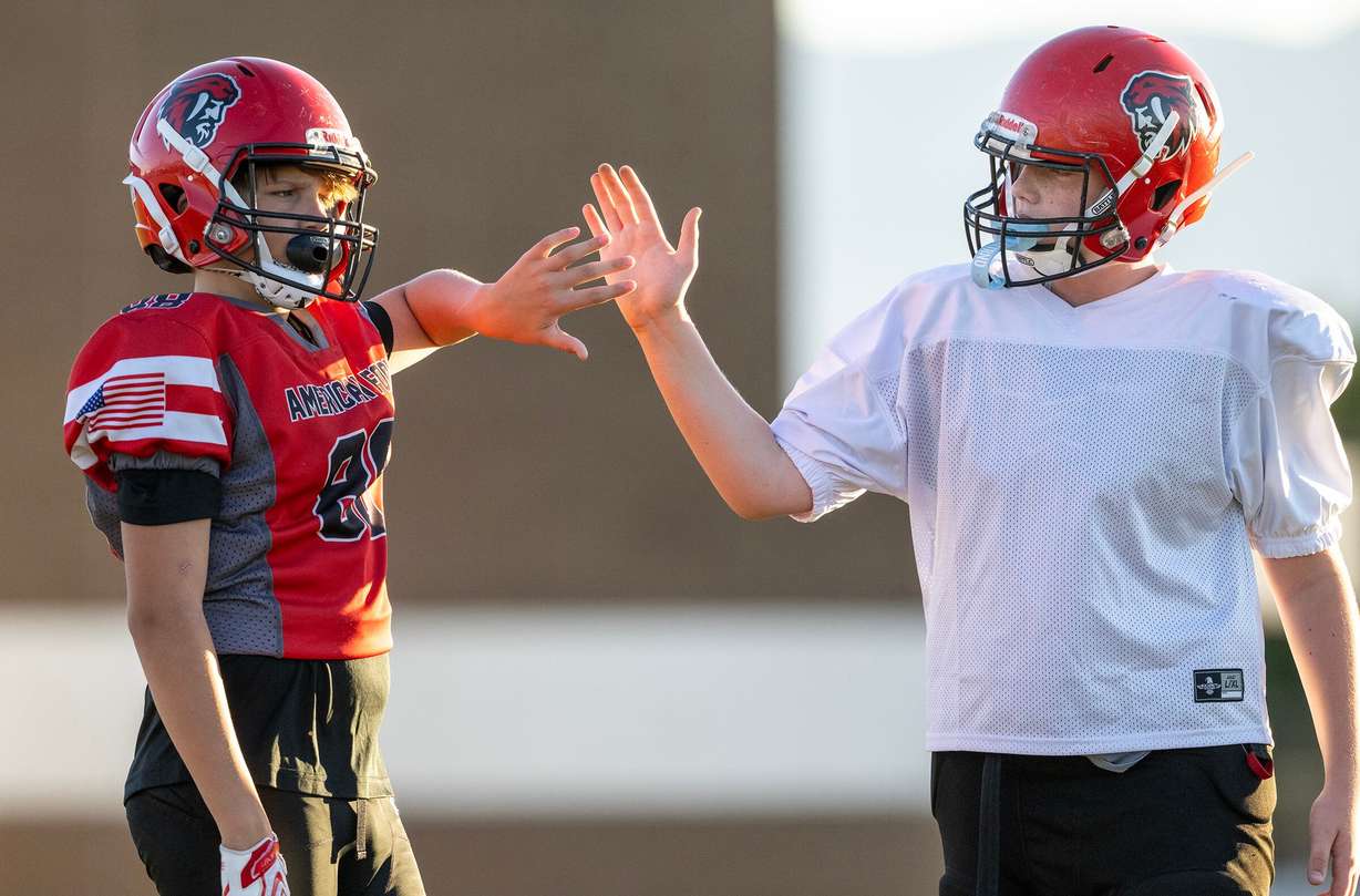 Logan North and Klasusian Sorensen high-five each other as members of a youth football team in American Fork go through their practice at American Fork Jr. High on Sept. 23. A new poll showed parents are comfortable with kids playing football nationwide — to an extent.
