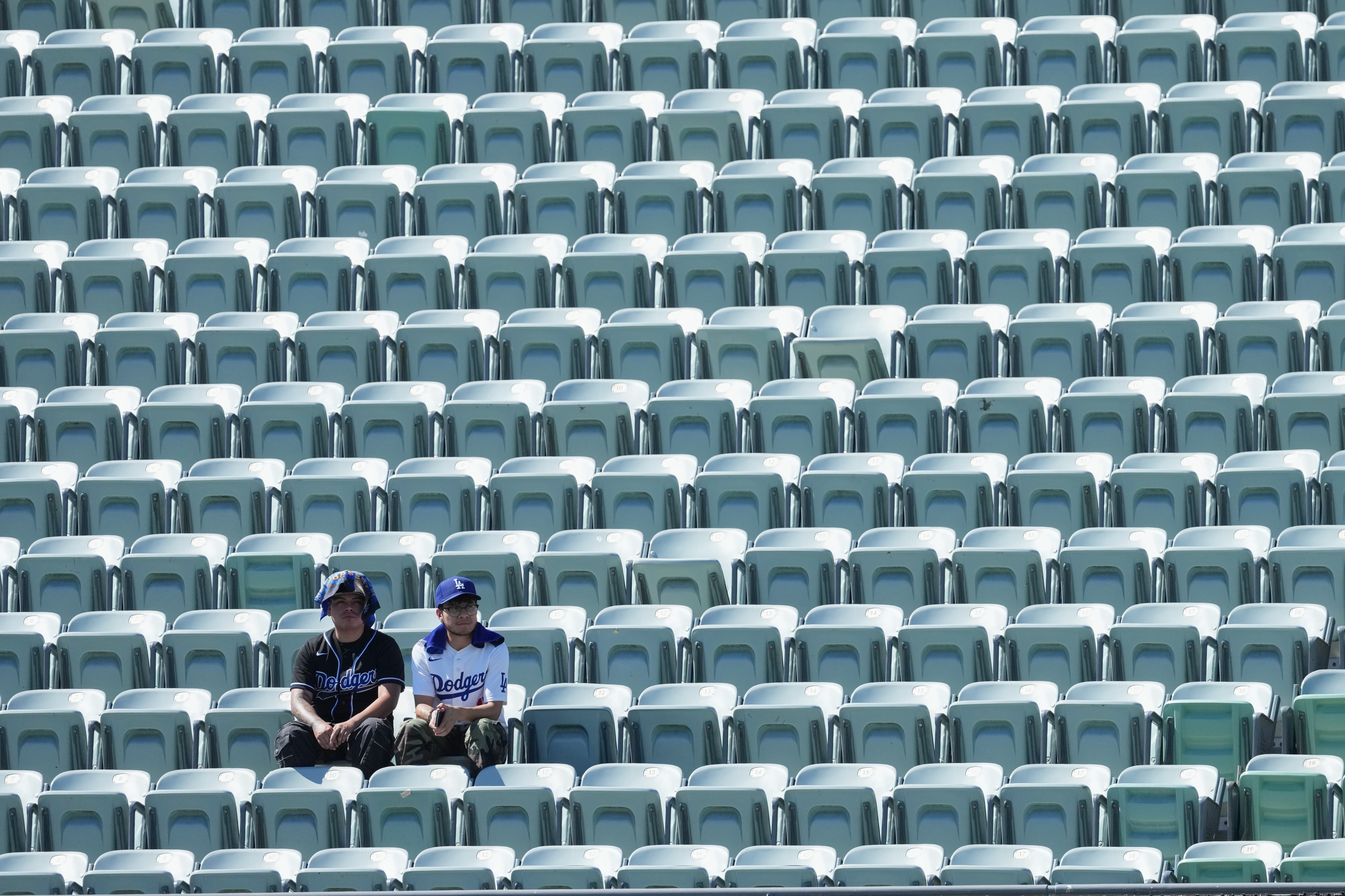 Los Angeles Dodgers fans look on among empty seats as they shield themselves from the sun and heat before Game 1 of a National League Division Series baseball game against the Atlanta Braves Saturday, Oct. 3, 2026, in Los Angeles. 