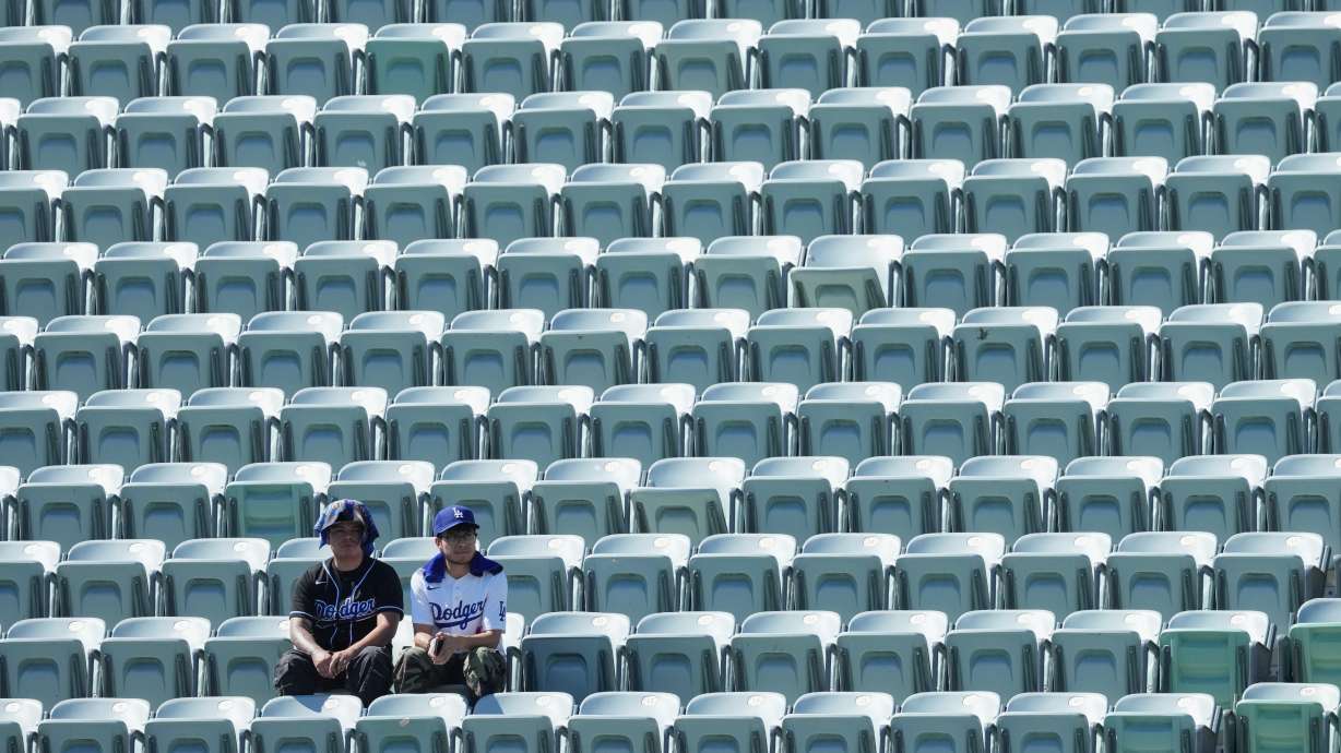 Los Angeles Dodgers fans look on among empty seats as they shield themselves from the sun and heat before Game 1 of a National League Division Series baseball game against the Atlanta Braves Saturday, Oct. 3, 2026, in Los Angeles.