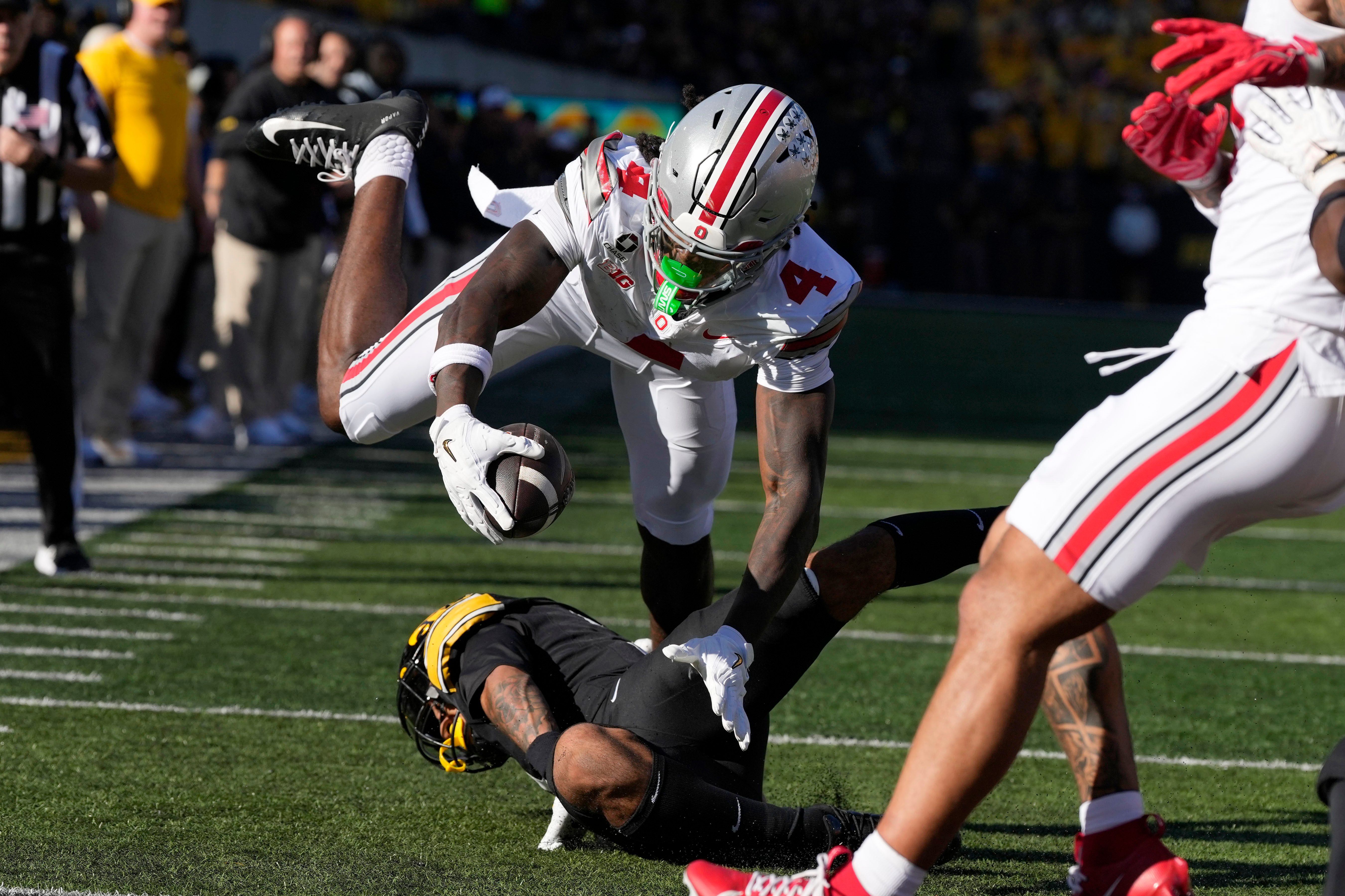 Ohio State wide receiver Jeremiah Smith (4) dives for a touchdown over Iowa defensive back Jaylen Watson during the first half of an NCAA college football game, Saturday, Oct. 3, 2026, in Iowa City, Iowa. 