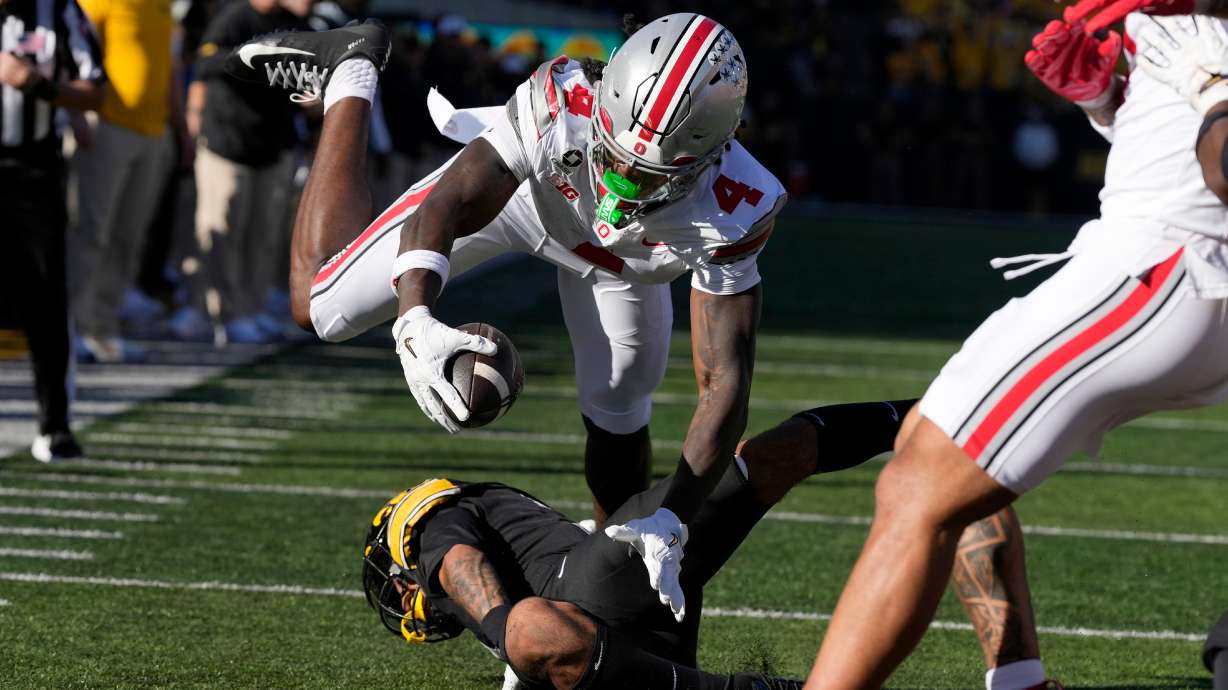 Ohio State wide receiver Jeremiah Smith (4) dives for a touchdown over Iowa defensive back Jaylen Watson during the first half of an NCAA college football game, Saturday, Oct. 3, 2026, in Iowa City, Iowa.