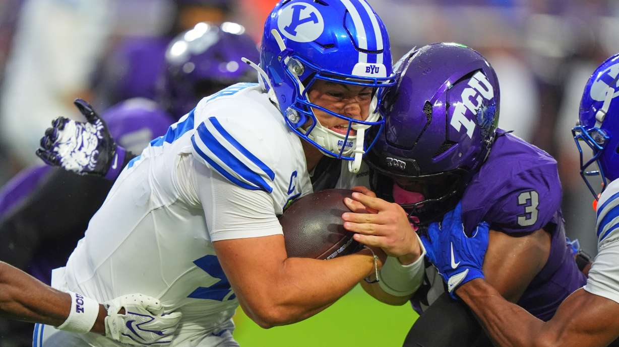 BYU quarterback Bear Bachmeier, left, runs against TCU linebacker Max Carroll (3) and other defenders during the first half of an NCAA college football game Saturday, Oct. 3, 2026, in Fort Worth, Texas.