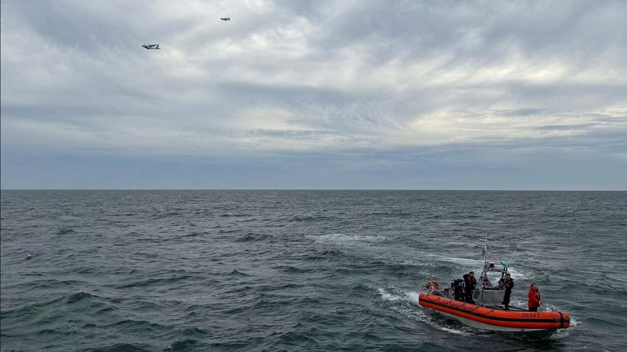 In this photo released by the U.S. Coast Guard, crew members search by air and on the water for a Boston-bound air ambulance that vanished off the coast of Nantucket, Mass., on Saturday. The search for the six missing people was suspended Sunday.