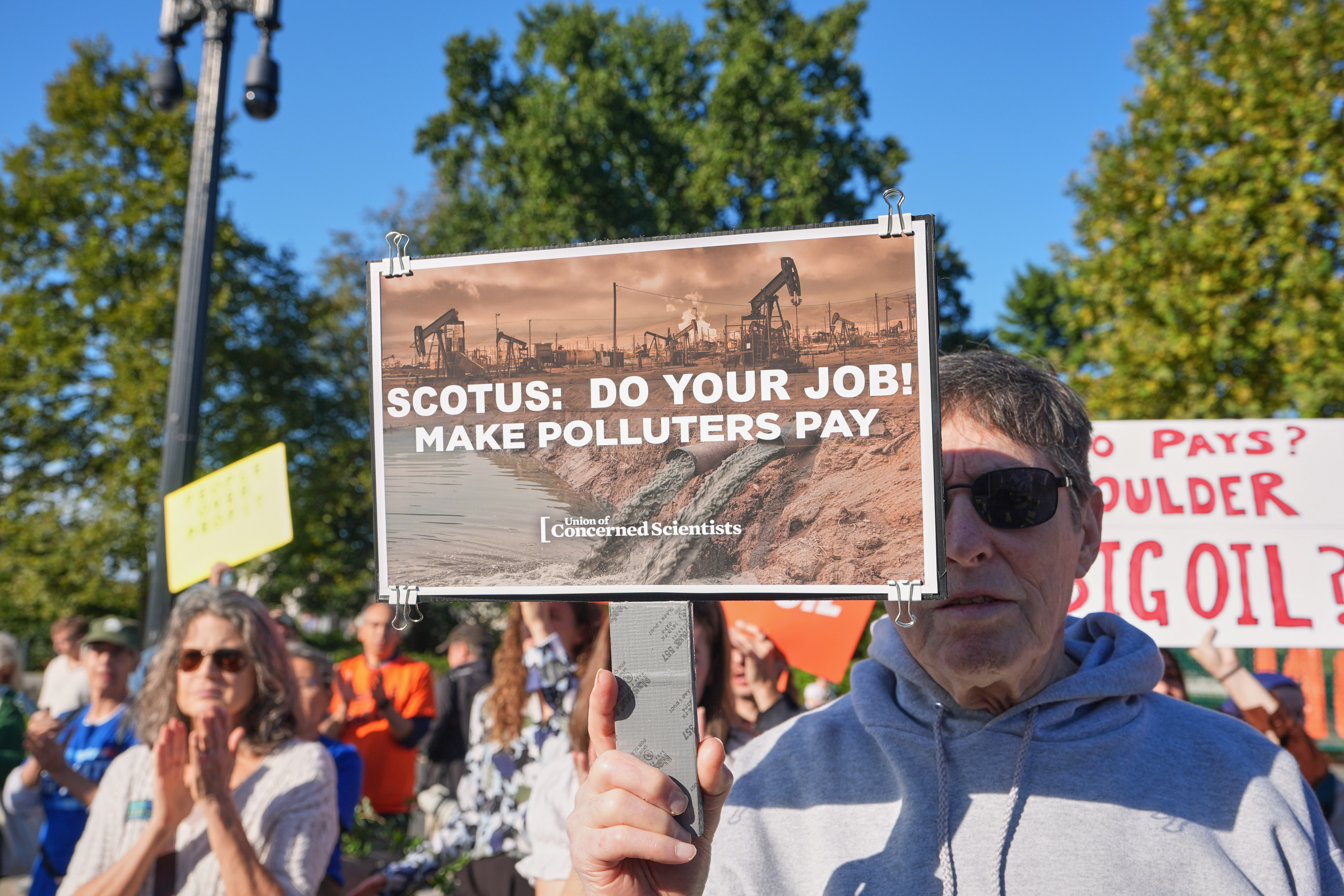 An activist carries a sign at the Supreme Court as the court begins its new term with a case about whether oil and gas companies should help pay for damage caused by disasters linked to climate change, on Capitol Hill, Oct. 5, in Washington. The United States' withdrawal from the Paris climate agreement has complicated efforts to combat climate change, the United Nations said on Wednesday.