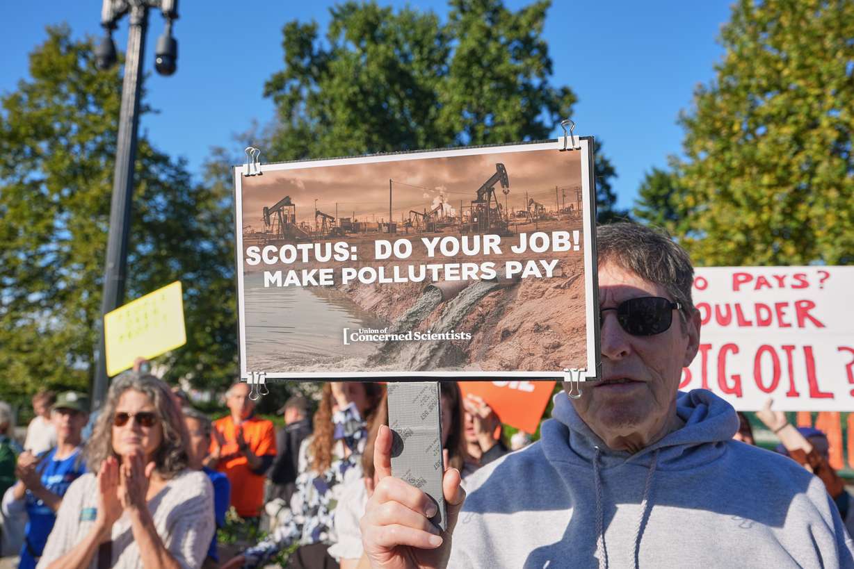 An activist carries a sign at the Supreme Court as the court begins its new term with a case about whether oil and gas companies should help pay for damage caused by disasters linked to climate change, on Capitol Hill, Oct. 5, in Washington. The United States' withdrawal from the Paris climate agreement has complicated efforts to combat climate change, the United Nations said on Wednesday.