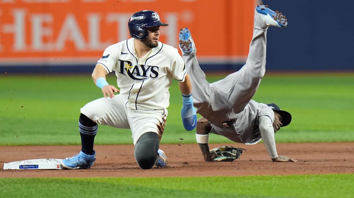 New York Yankees second baseman Jazz Chisholm Jr., right, flips over Tampa Bay Rays' Jonathan Aranda, left, while committing a throwing error allowing Rays' Yandy Díaz to score during the first inning in Game 2 of an American League Division Series baseball game Monday, Oct. 5, 2026, in St. Petersburg, Fla.