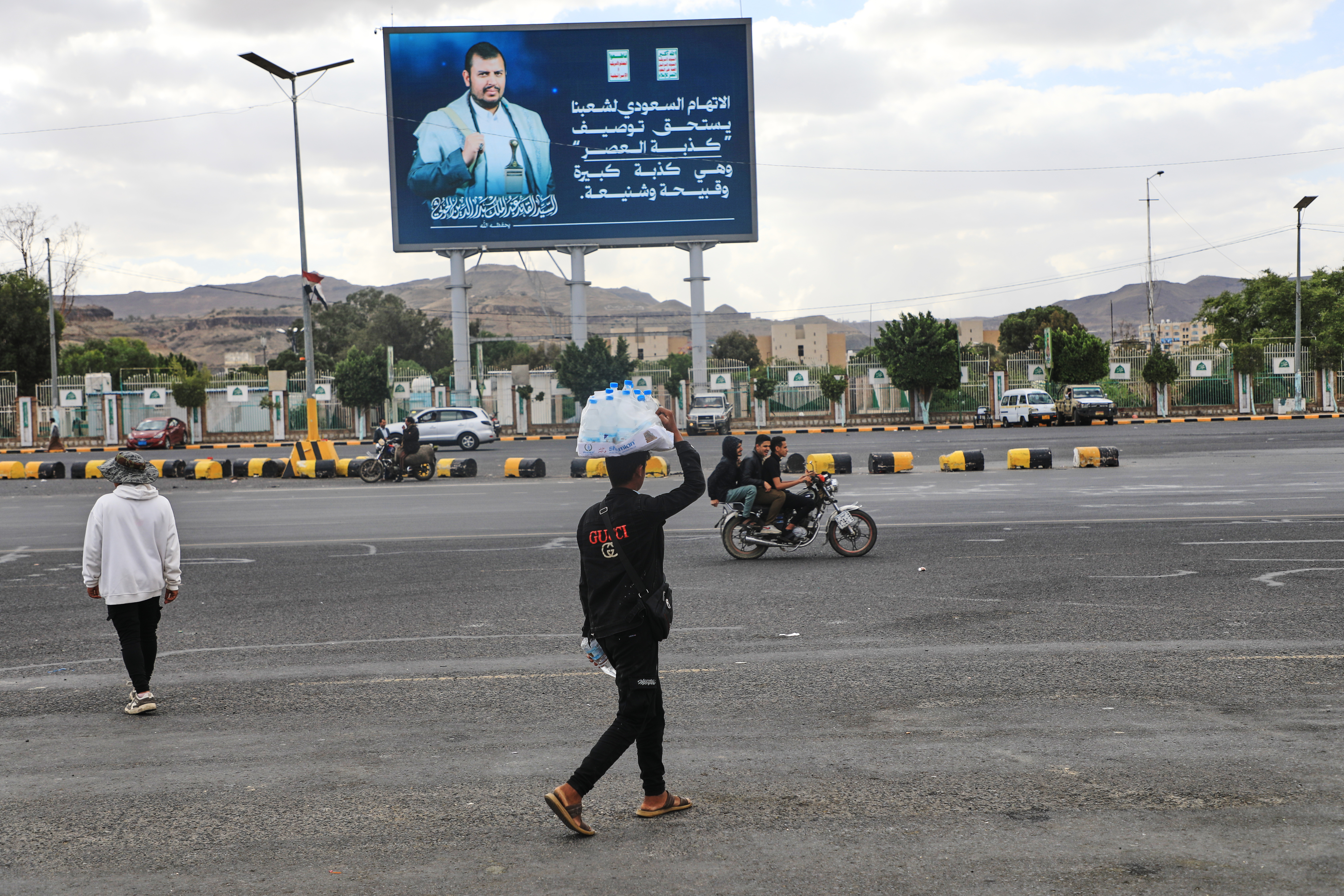 A vendor walks under a billboard showing Houthi leader Abdul Malik al-Houthi in Sanaa, Yemen, Oct. 5. A member of the Houthi's bureau said the group is welcome to any mediation to end the Yemeni civil war it's involved in.