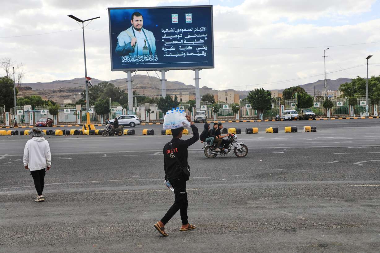 A vendor walks under a billboard showing Houthi leader Abdul Malik al-Houthi in Sanaa, Yemen, Oct. 5. A member of the Houthi's bureau said the group is welcome to any mediation to end the Yemeni civil war it's involved in.