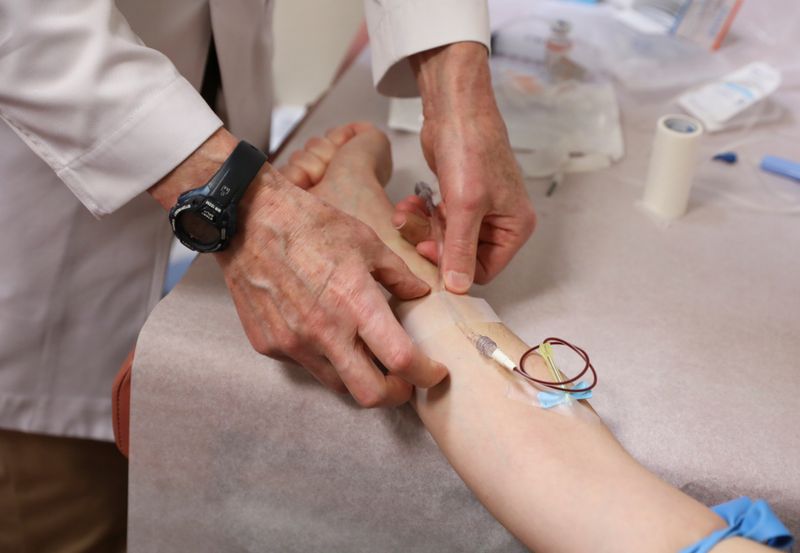 FILE PHOTO: A doctor adjusts an IV to administer medication to a patient undergoing treatment in Manhattan, New York, US, May 1, 2020.
