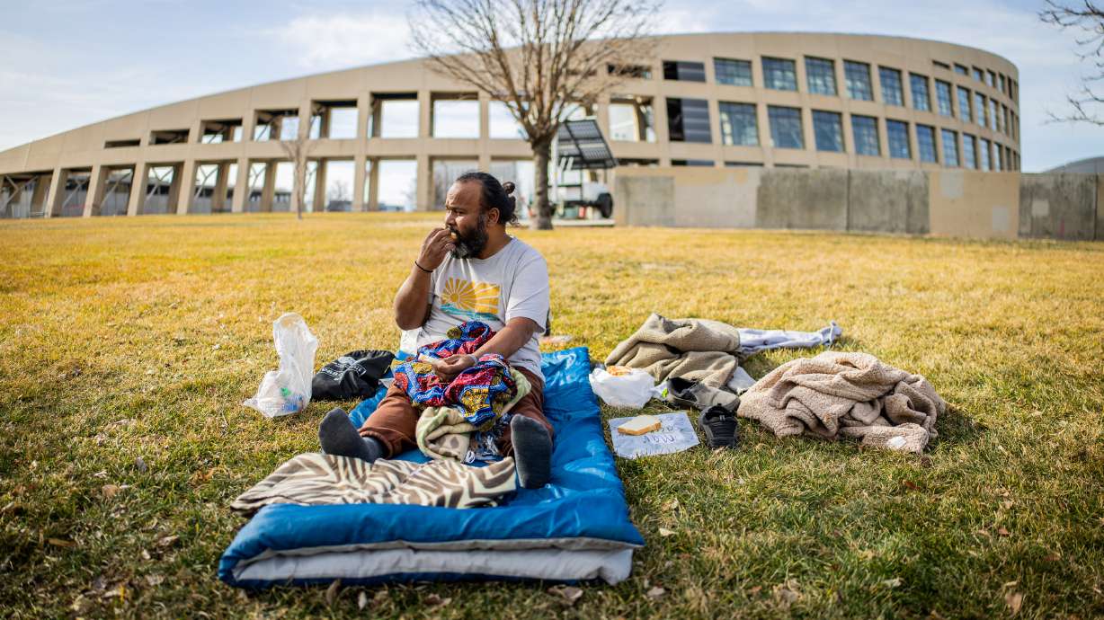 Jacob Myra Omar, a person experiencing homelessness, eats lunch outside the Salt Lake City Public Library before going inside the library to take a nap in Salt Lake City on Feb. 3. Utah's Homeless Services Board voted Tuesday to approve more than $1.8 million to three cities that host temporary winter shelter space.
