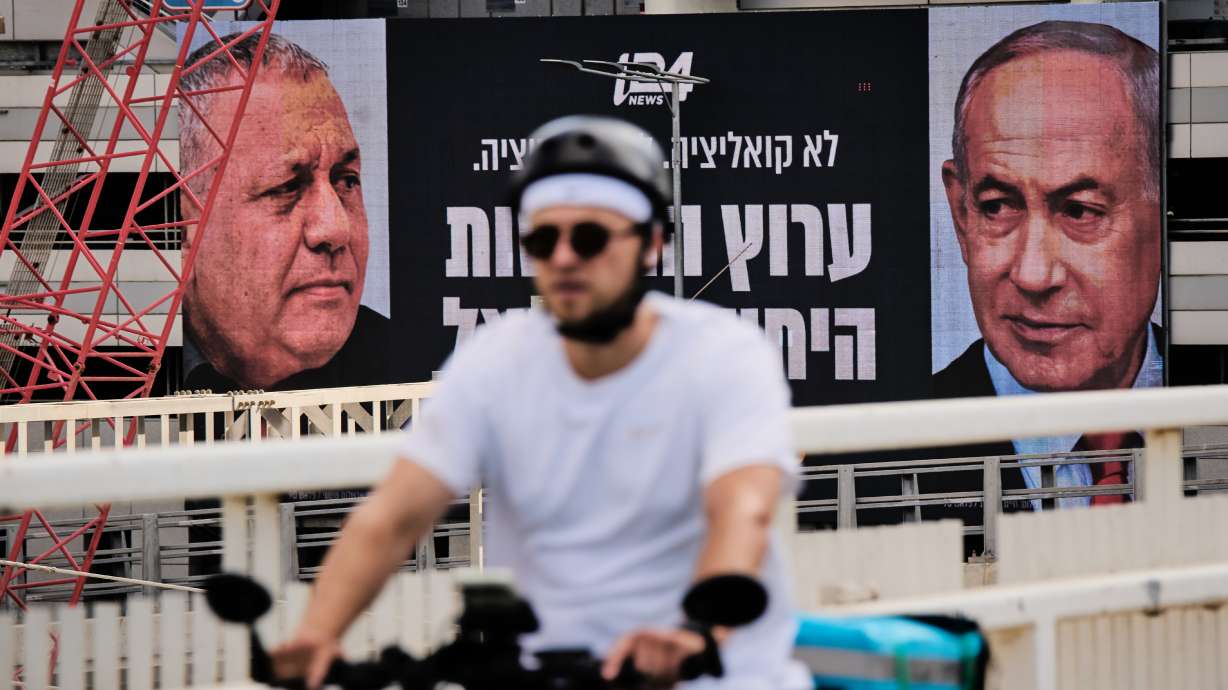 A man rides bicycle past a television channel advertisement featuring Israeli Prime Minister Benjamin Netanyahu, right, and his main rival, opposition candidate Gadi Eisenkot, ahead of Israel's general election, in Ramat Gan, Israel, Sept. 23.
