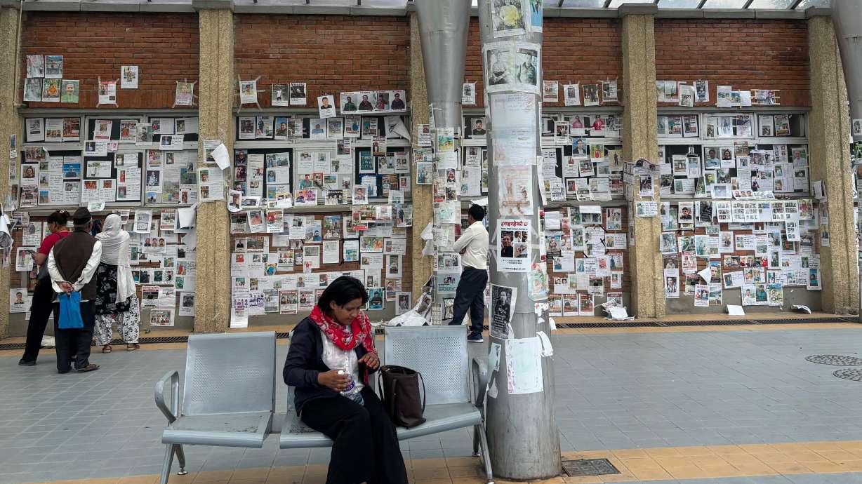 In this photo taken with a smartphone, people look at photographs of hundreds of people missing since last month’s floods, posted on a wall by relatives hoping to receive information about them at Tribhuvan University Teaching Hospital, in Kathmandu, Nepal, Thursday, Sept. 17. The families of thousands of people who remain missing in Nepal weeks after floods devastated the country have expressed mixed feelings after the government said this week that it is stopping the search for victims.