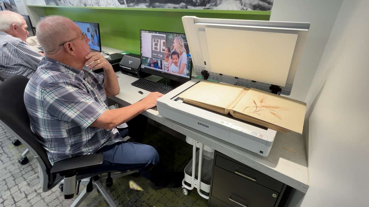 Richard Selvage scanning old scrapbook photos to become digital photos on a flash drive.