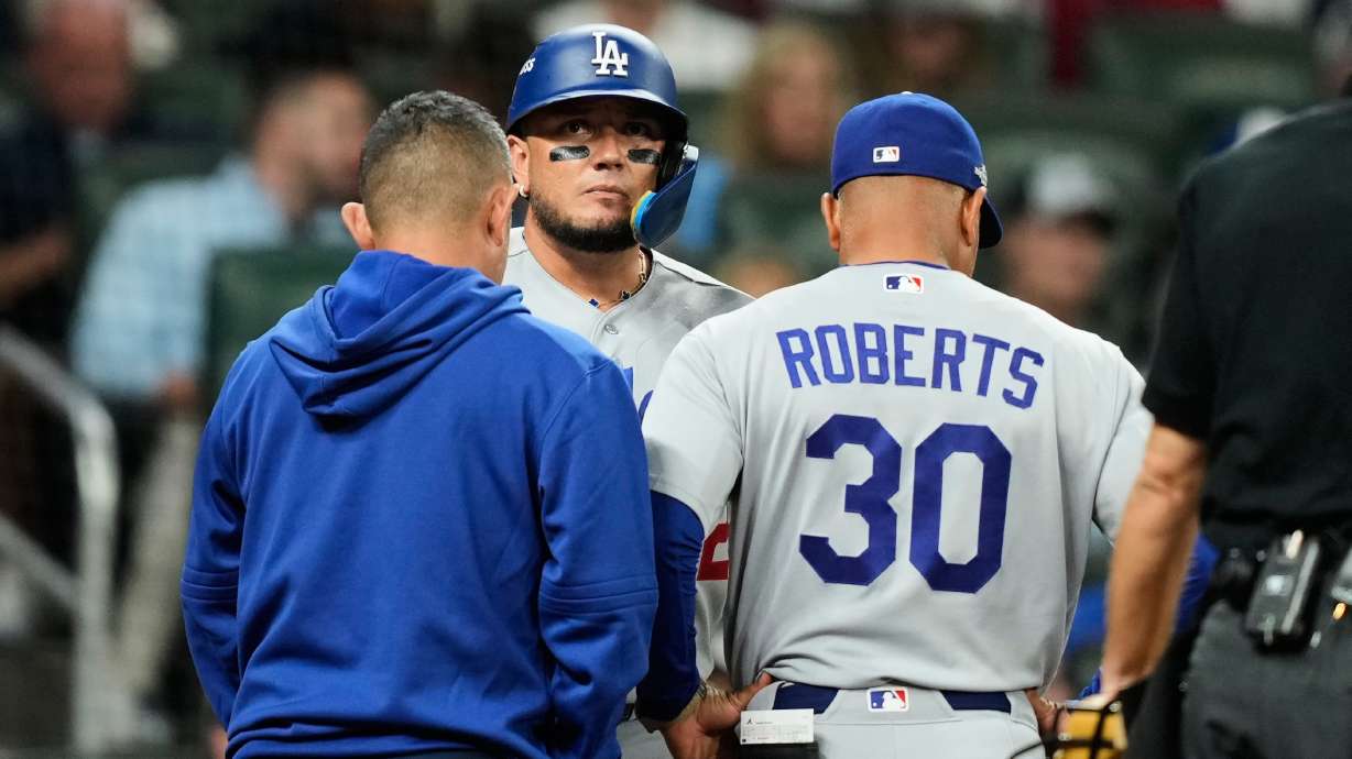 Los Angeles Dodgers' Miguel Rojas talks with manager Dave Roberts (30) and a member of the staff before leaving the game during the eighth inning in Game 3 of baseball's National League Division Series against the Atlanta Braves, Tuesday, Oct. 6, 2026, in Atlanta.