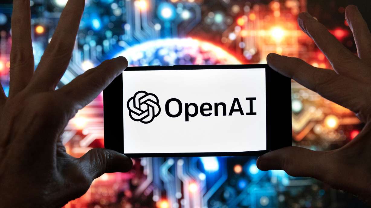 The OpenAI logo is displayed on a cell phone in front of an image generated by ChatGPT's Dall-E text-to-image model, Dec. 8, 2023, in Boston.