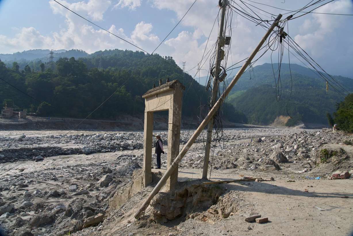 A man stands next to a gate damaged by a flash flood in Rasuwa, Nepal, Friday, Oct. 2.