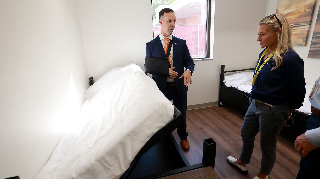 Luke Lassiter, Utah Department of Corrections Orange Street Community Correctional Center captain, shows Suzette Sipple, a religious services volunteer, under-bed storage in Orange Street Community Correctional Center bedrooms during a ribbon-cutting ceremony for ARCH Project, aimed at helping break the cycle of recidivism and homelessness, in Salt Lake City on Wednesday.